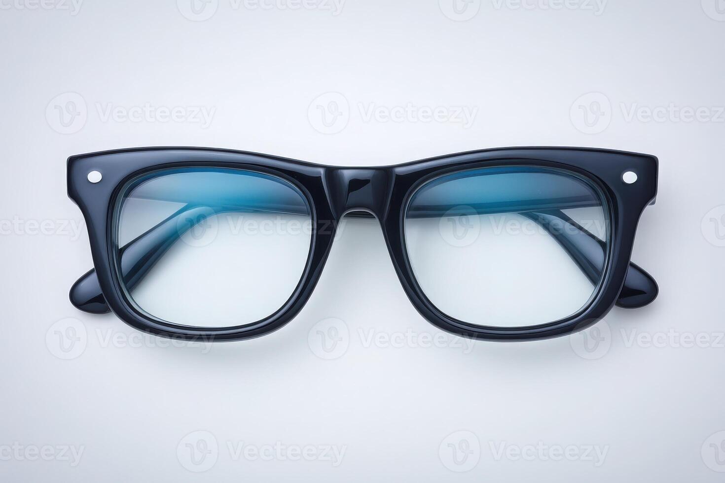 Black framed glasses with a sleek design rest on a neutral surface. The glasses feature blue-tinted lenses, creating a stylish contrast against the simple backdrop. photo