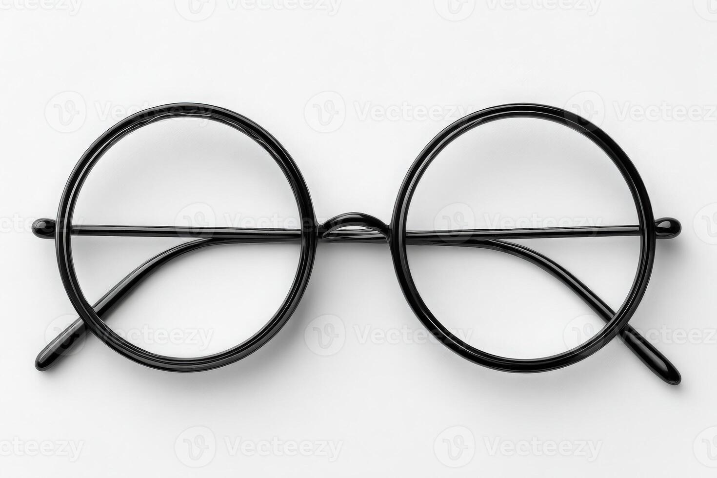 A pair of round black eyeglasses rests flat on a white background. The simple design features a thin wire frame and clear lenses. Ideal for those needing vision correction or as a fashion statement. photo