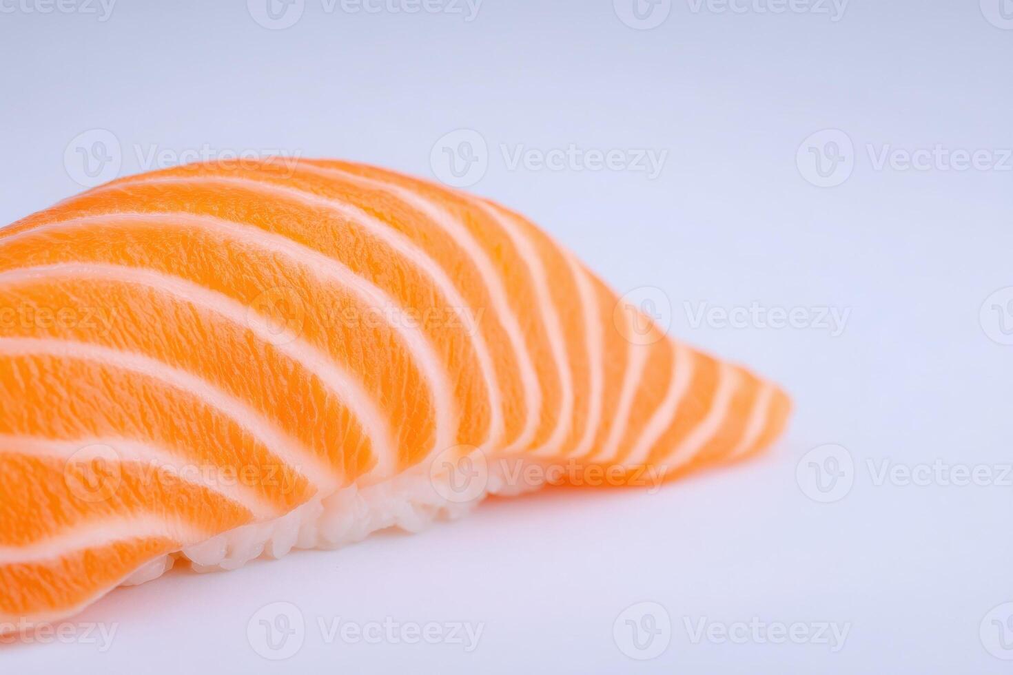 A vibrant piece of salmon sushi showcases its delicate texture and rich color. The sushi is placed on a pristine white background, highlighting its appealing presentation. photo