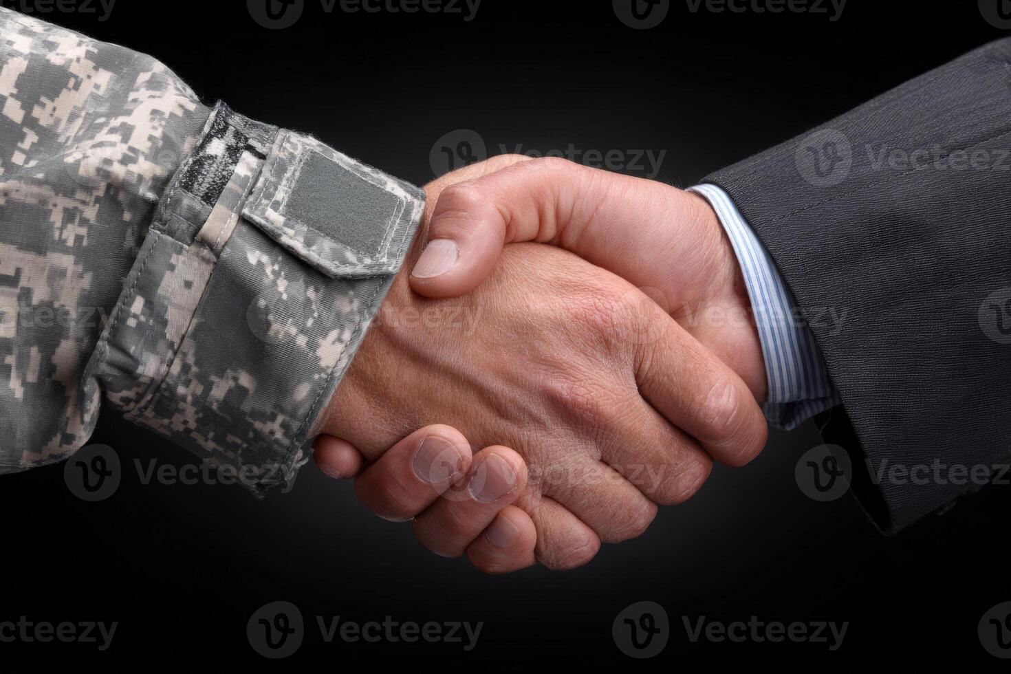 A military member in camouflaged uniform shakes hands with a civilian in a formal suit. This gesture symbolizes unity, cooperation, and an understanding between diverse sectors. photo