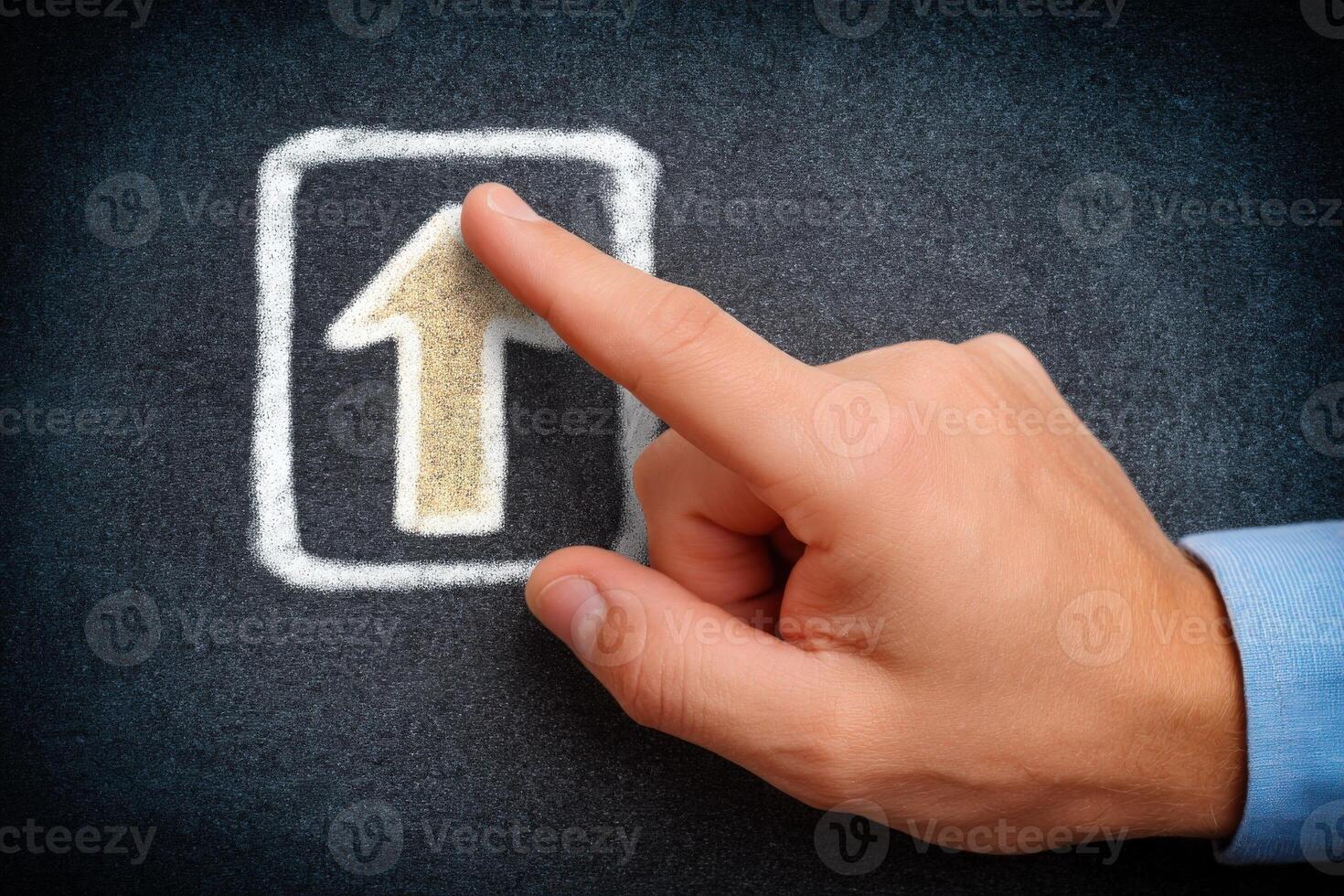 A hand with a light skin tone points at a chalk drawing of an upward arrow on a dark board. This moment captures creativity and intention, highlighting a dynamic learning or brainstorming environment. photo