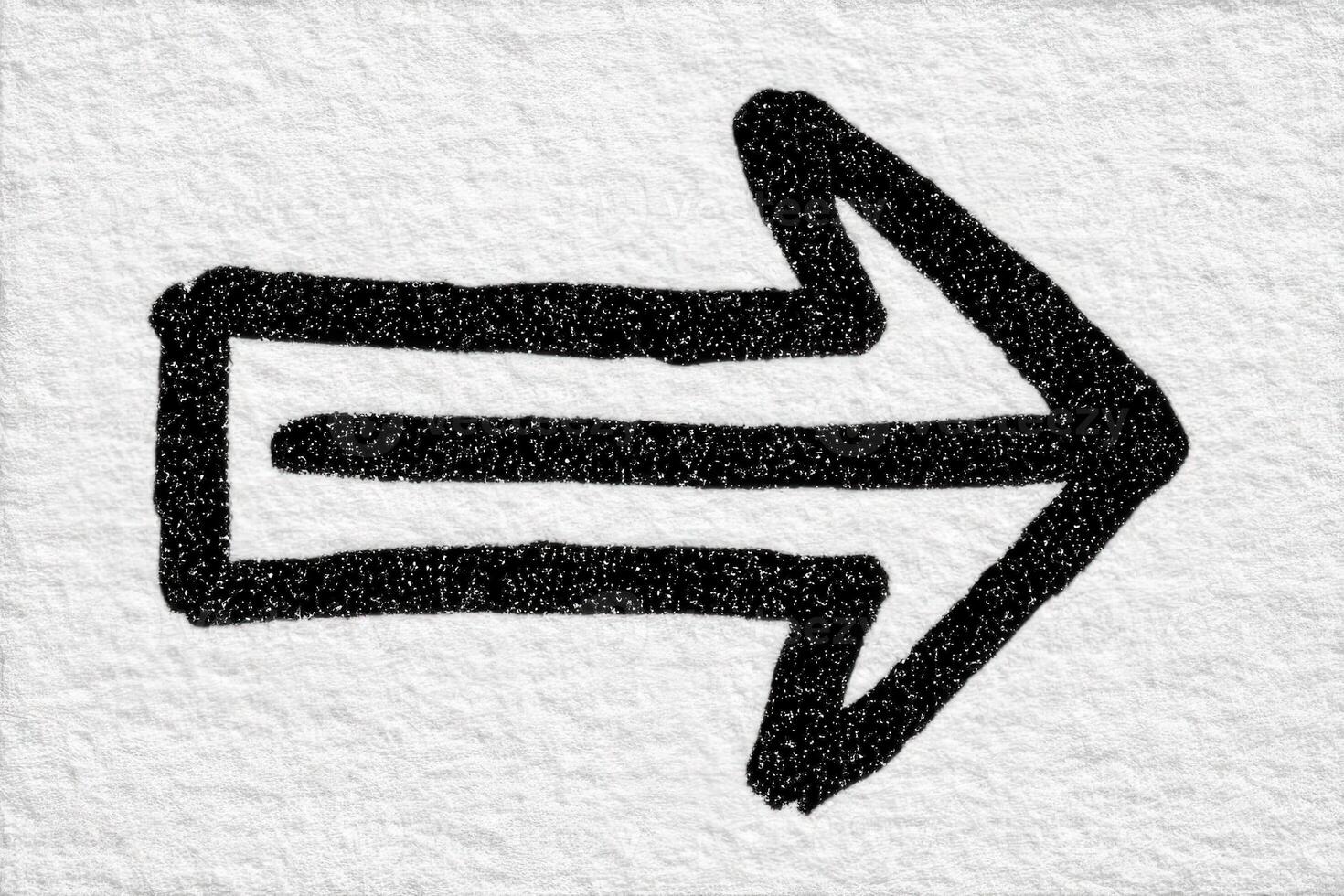 A bold black arrow is drawn on a textured, light background, indicating direction to the right. The arrows simplicity emphasizes clarity and purpose in visual communication. photo