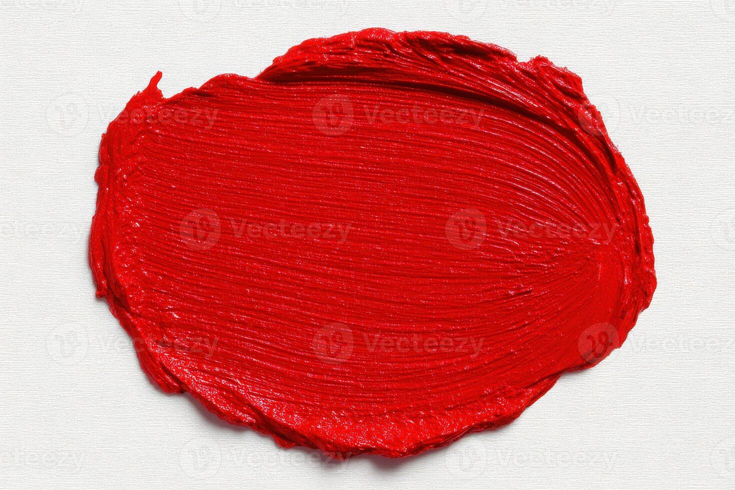 A thick layer of bright red paint is spread on a textured canvas, showcasing its rich color and smooth texture. The paint appears freshly applied, hinting at a creative endeavor in progress. photo