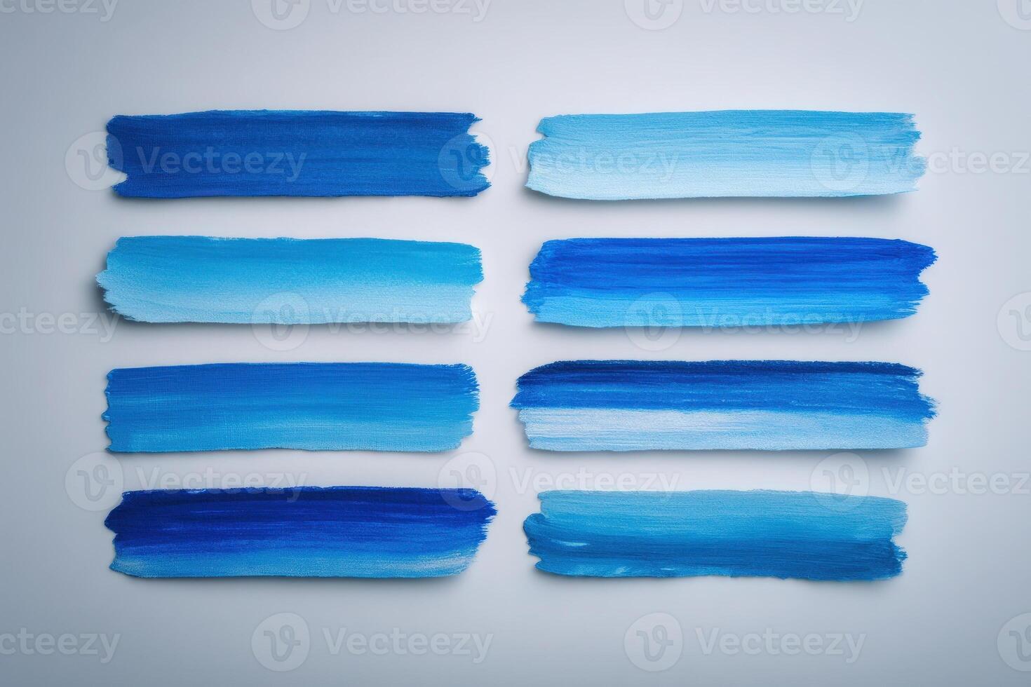 A creative arrangement of blue paint strokes on a light surface showcases different shades, blending from deep navy to soft azure. This artistic display highlights color variation and texture. photo