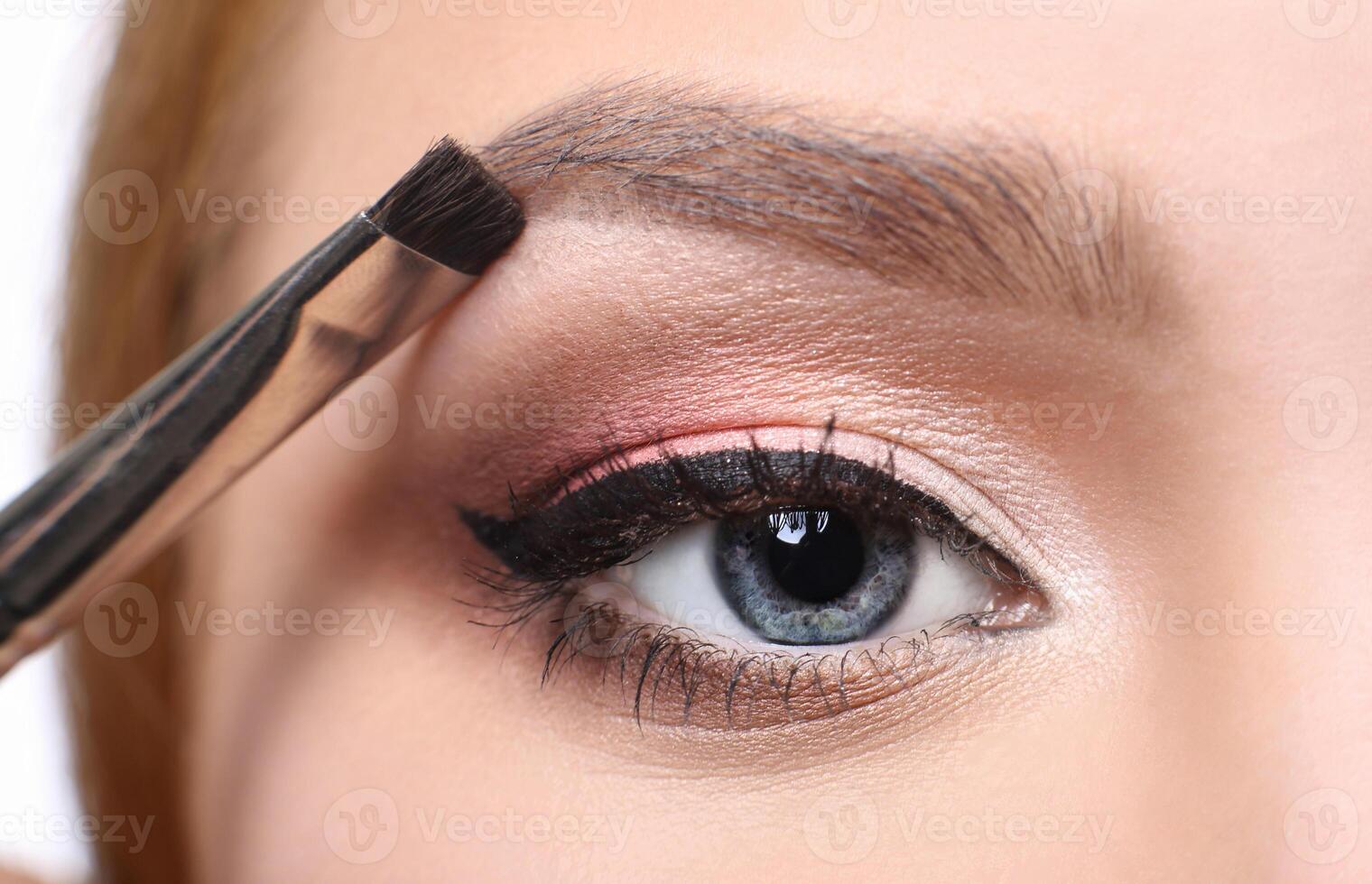 Eyebrow shadow applying, brow modelling makeup, eye closeup. Female model face with fashion make-up, beauty concept isolated photo