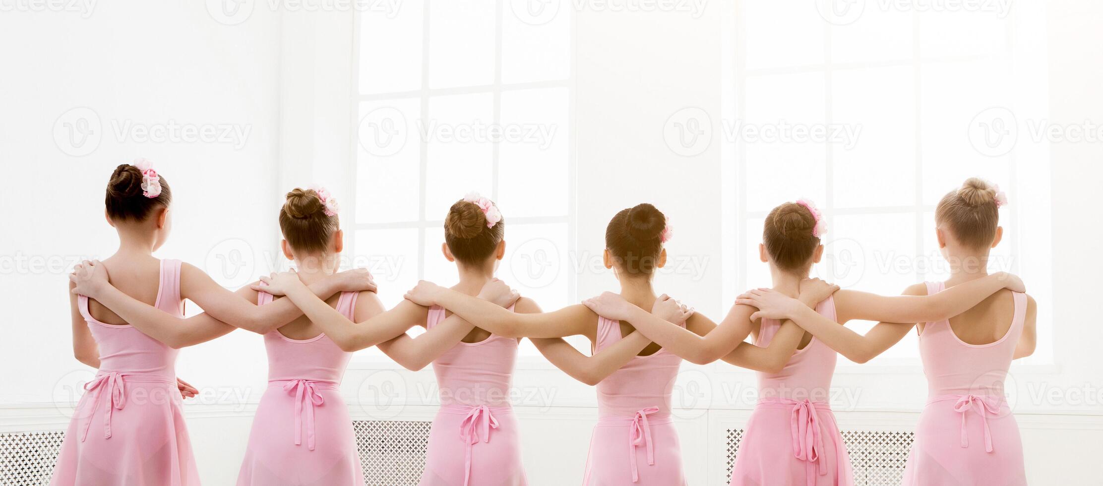 Young girls dancing ballet in studio. Choreographed dance by a group of graceful pretty young ballerinas practicing during class before performance. Classical dance school photo