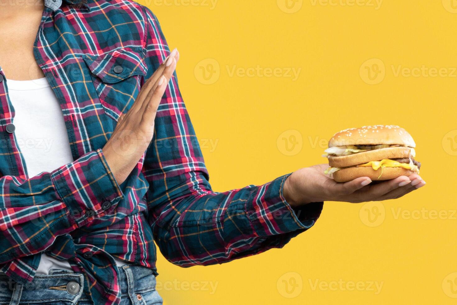 Refuse Fast Food. Portrait Of Unhappy African American Woman Holding Burger And Showing Stop Gesture With Palm. Black Lady Rejecting Unhealthy Sandwich, Isolated Over Orange Background, Banner photo
