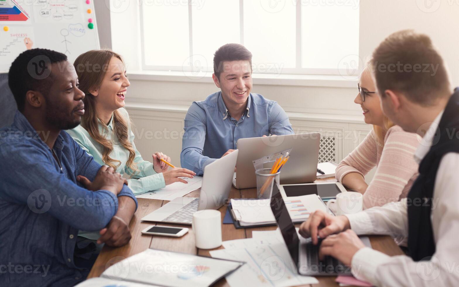 Business corporate meeting of multiethnic team. Young cheerful people brainstorming, discussing new startup project in office, copy space photo