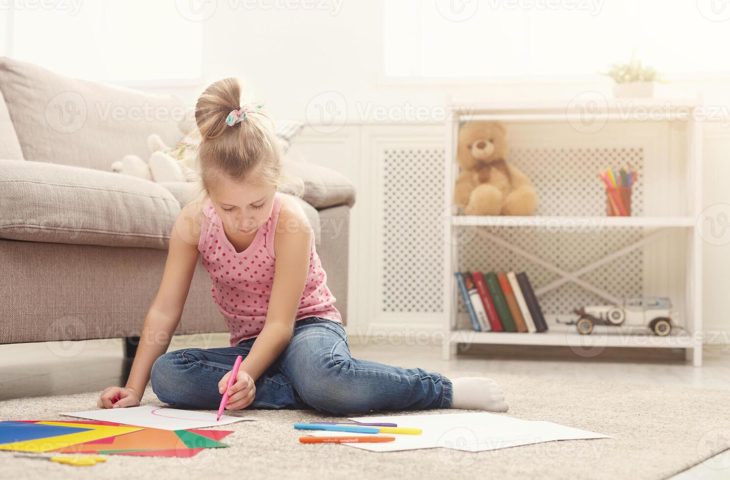 Happy little girl drawing. Cute kid sitting at home on the floor among cologed paper and pencils. DIY, creative art hobby, early development and inspiration concept photo