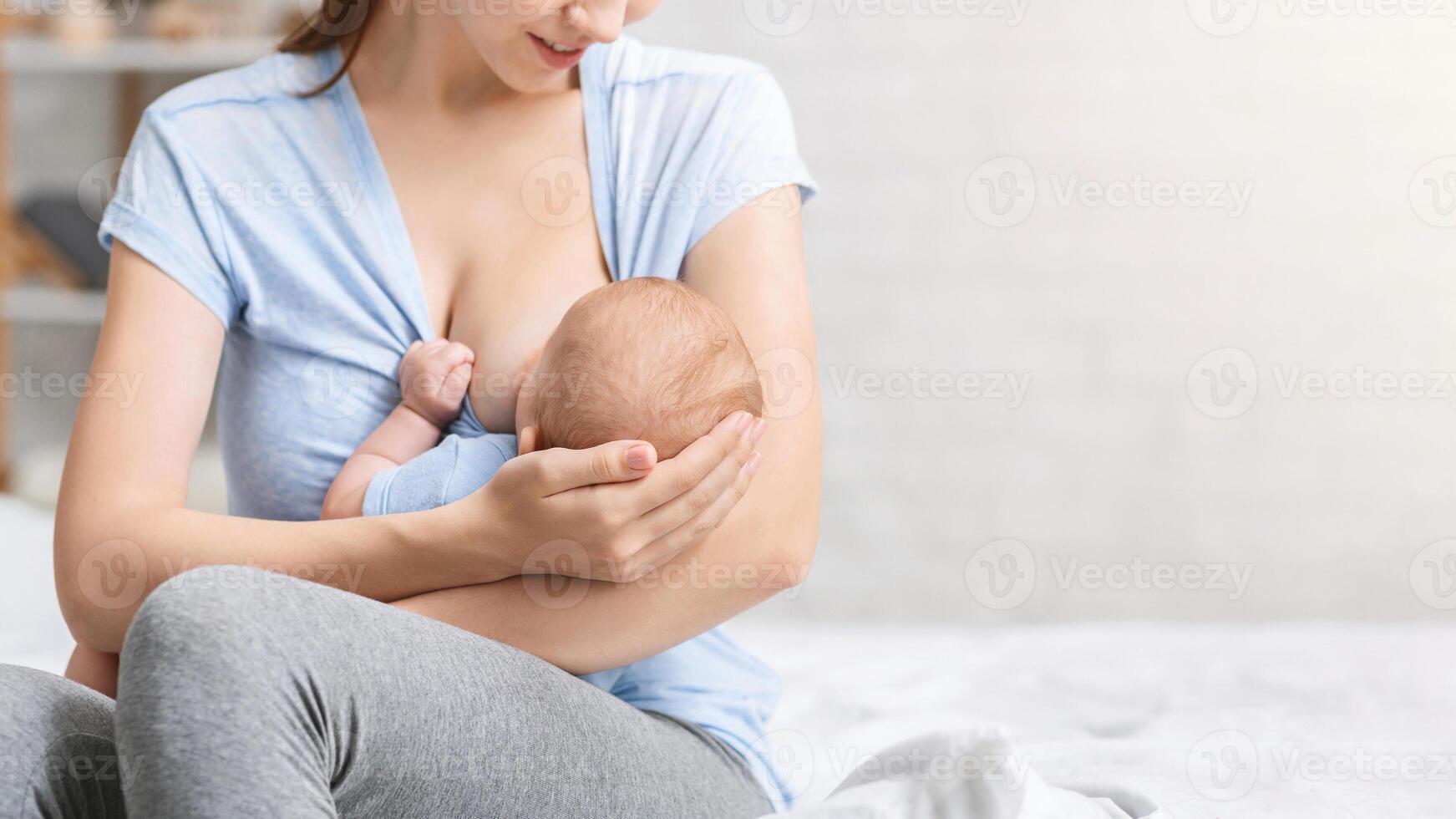 Happy motherhood. Caring mother enjoying breastfeeding of her baby at home, empty space photo