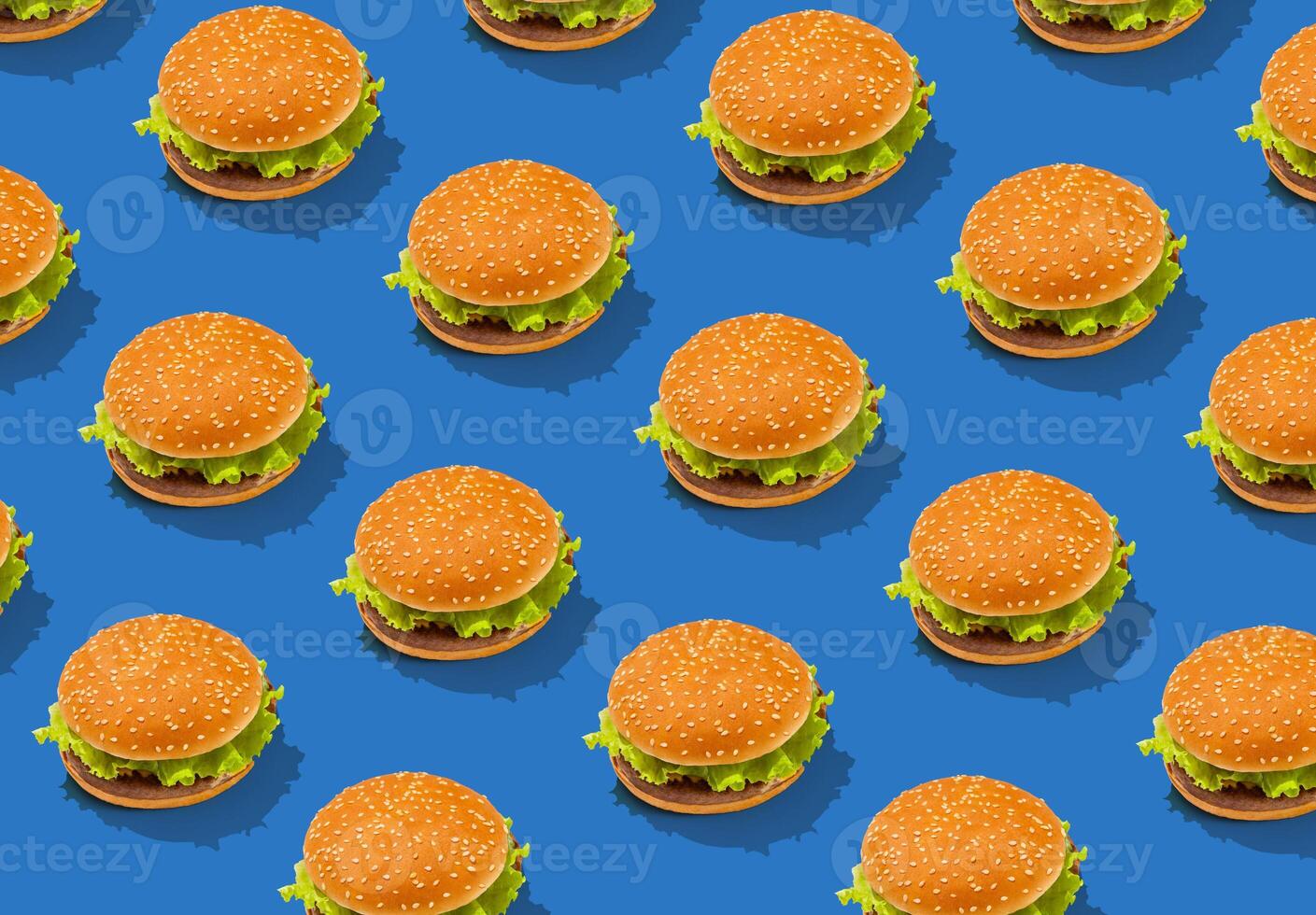 Tasty fresh hamburgers with lettuce and sesame bun on blue background, creative design, repeat pattern, top view photo