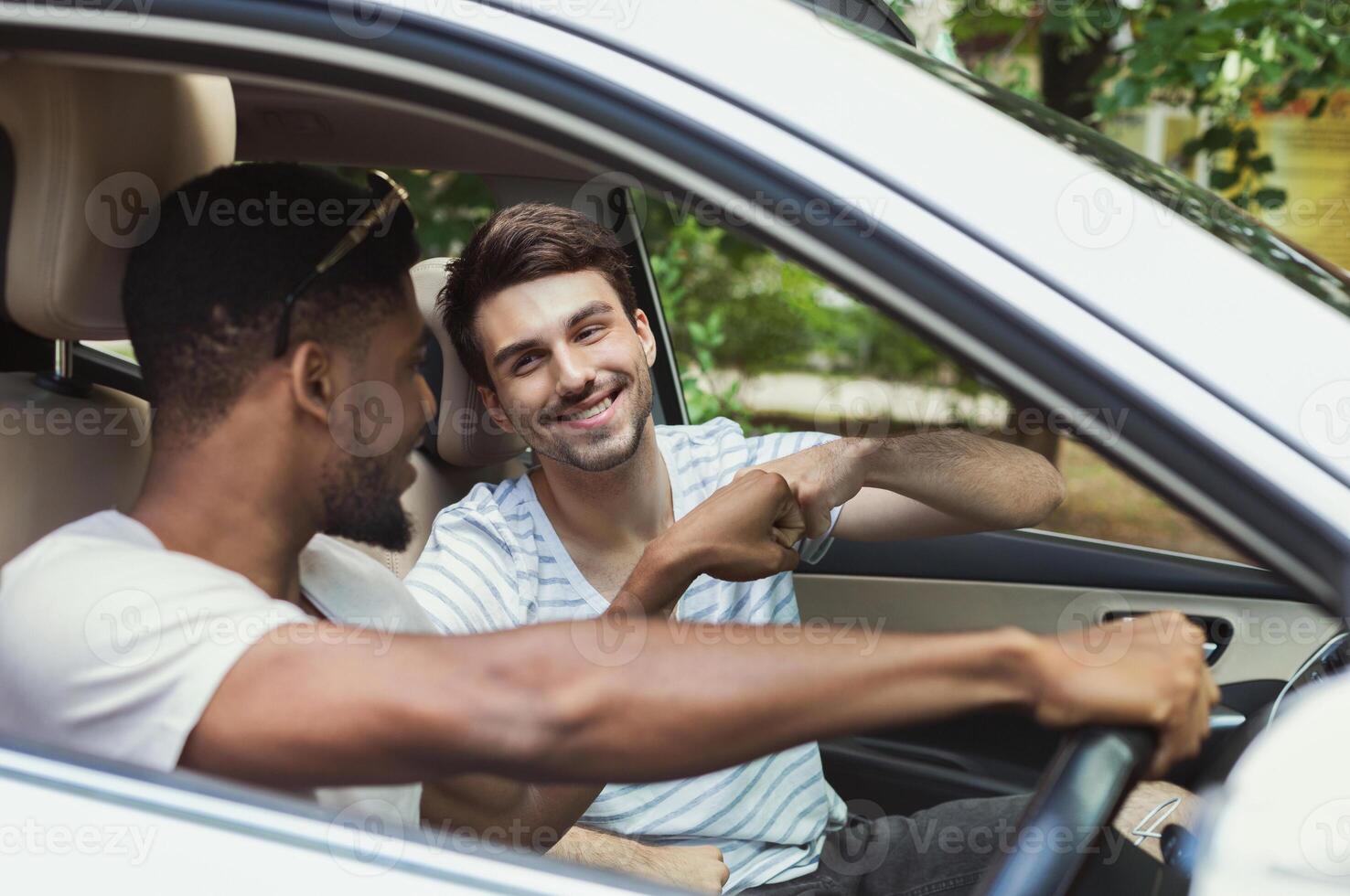 Happy millennials friends traveling by car,making fist bump photo