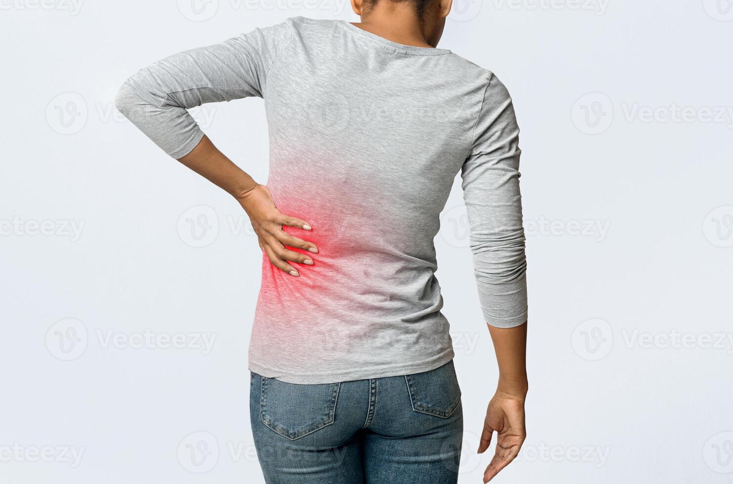 Kidney stones. Afro woman holding her hand behind back, pain in kidney, inflamed zone highlighted in red, back view photo