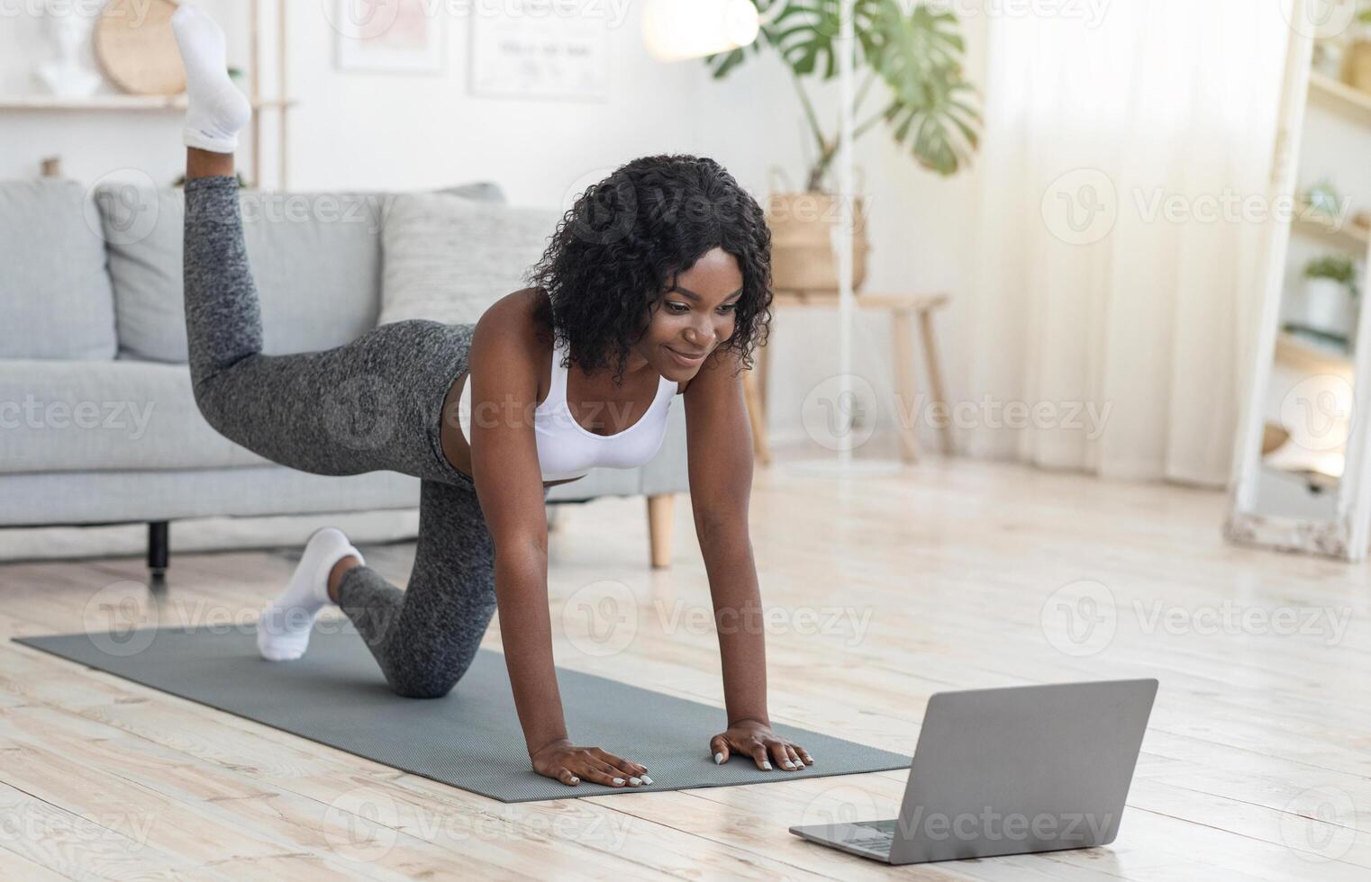 African american girl exercising with online tutorial on laptop at home, empty space photo