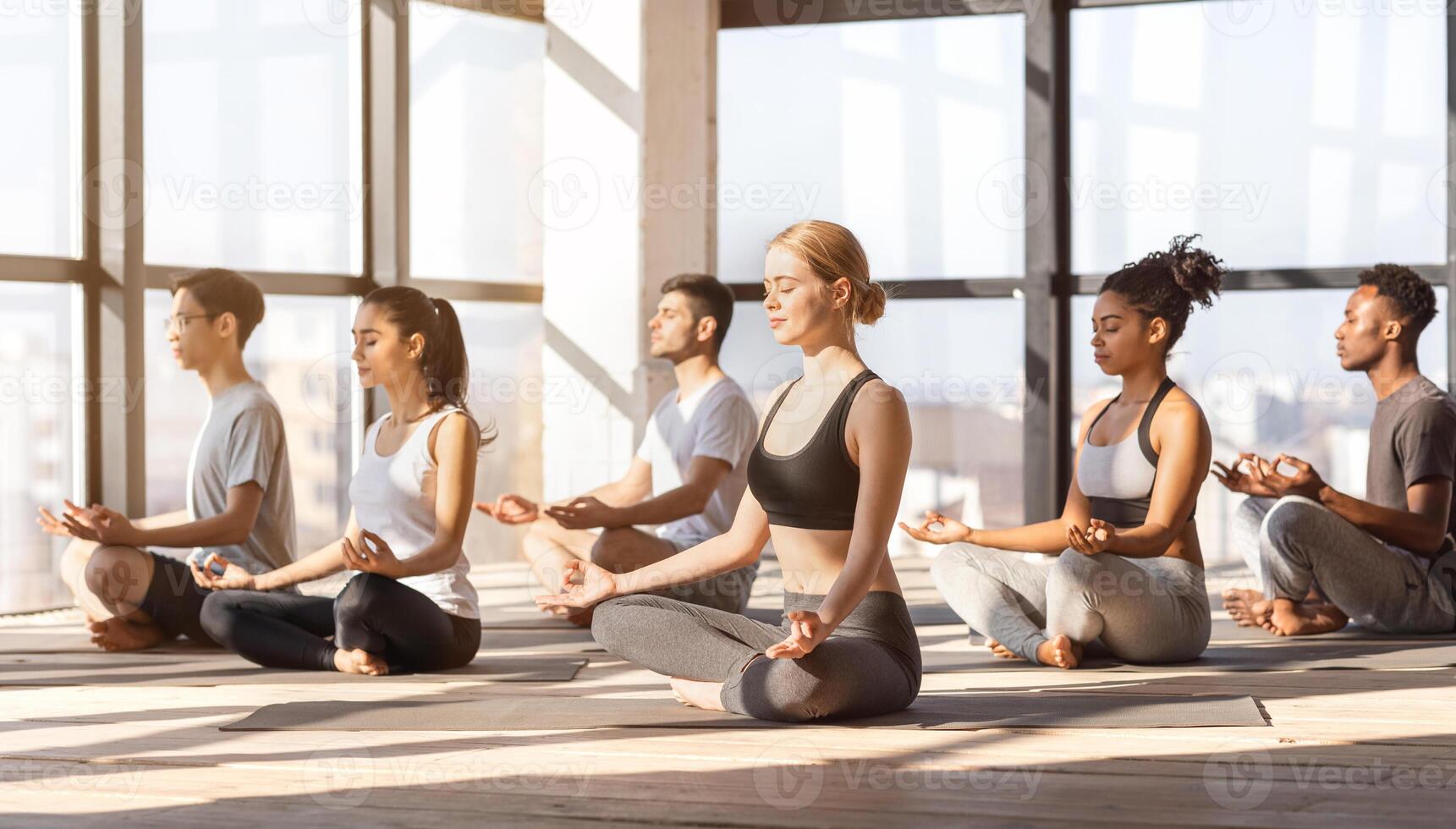 Group Yoga Practice. Relaxed Multiracial People Meditating With Closed Eyes In Studio Together, Free Space photo