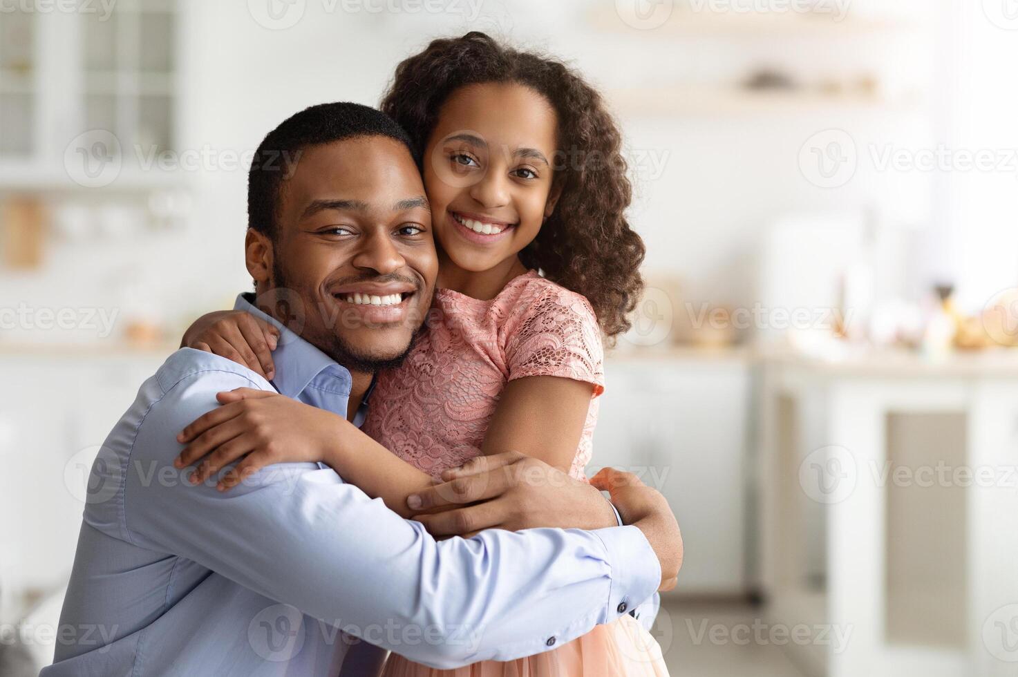 Loving black family young father and little daughter hugging while spending time together at home, closeup portrait, copy space. Happy african american school girl embracing her smiling daddy photo