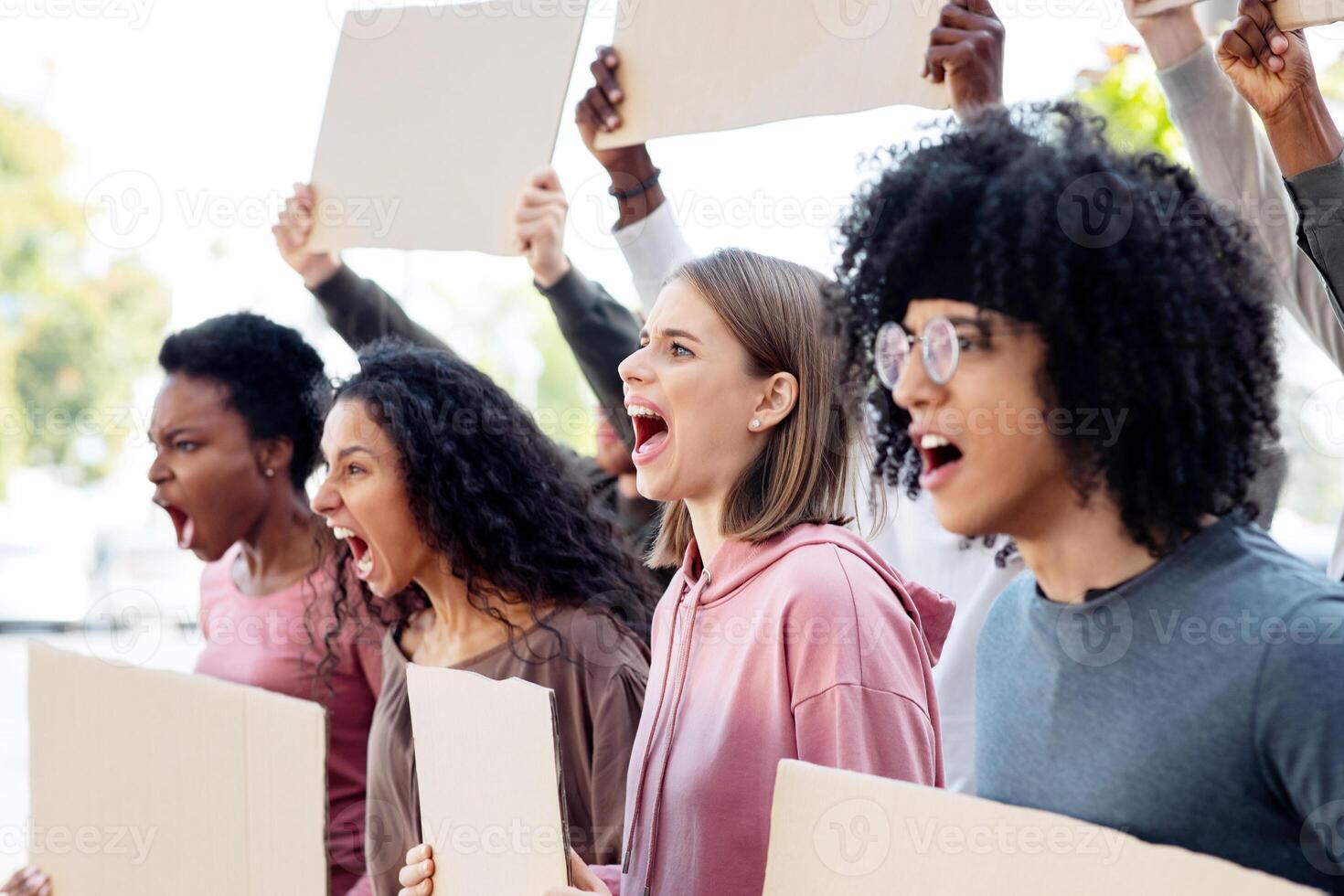 Motivated group of international students with blank placards making protest outdoors, chanting slogans towards government building. Multiracial demonstrators with empty boards walking by street photo