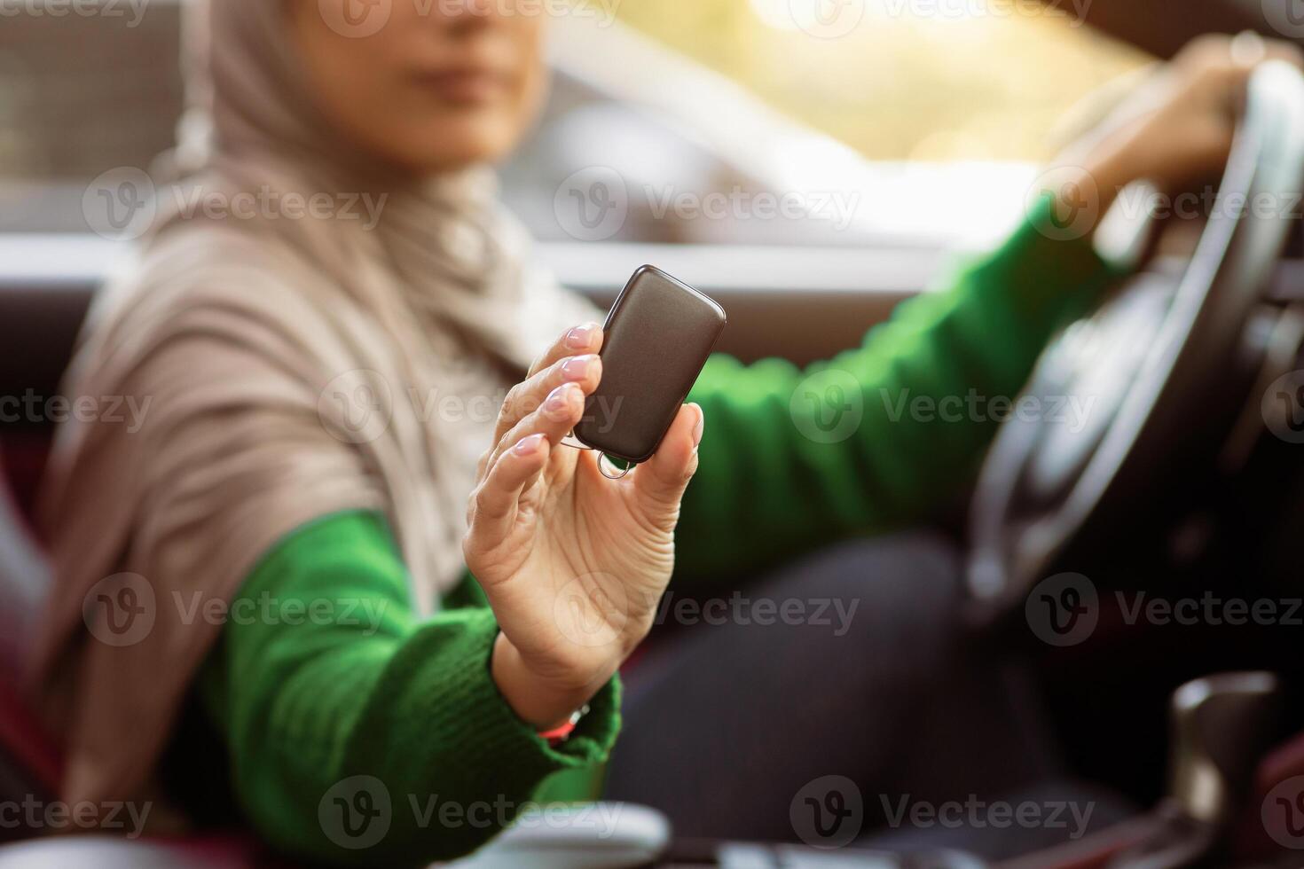 Unrecognizable Muslim Woman In Hijab Showing Automobile Keys Sitting In Her New Vehicle On Driver's Seat. Middle East Female Client Choosing Auto Transport In Dealership Showroom Store photo