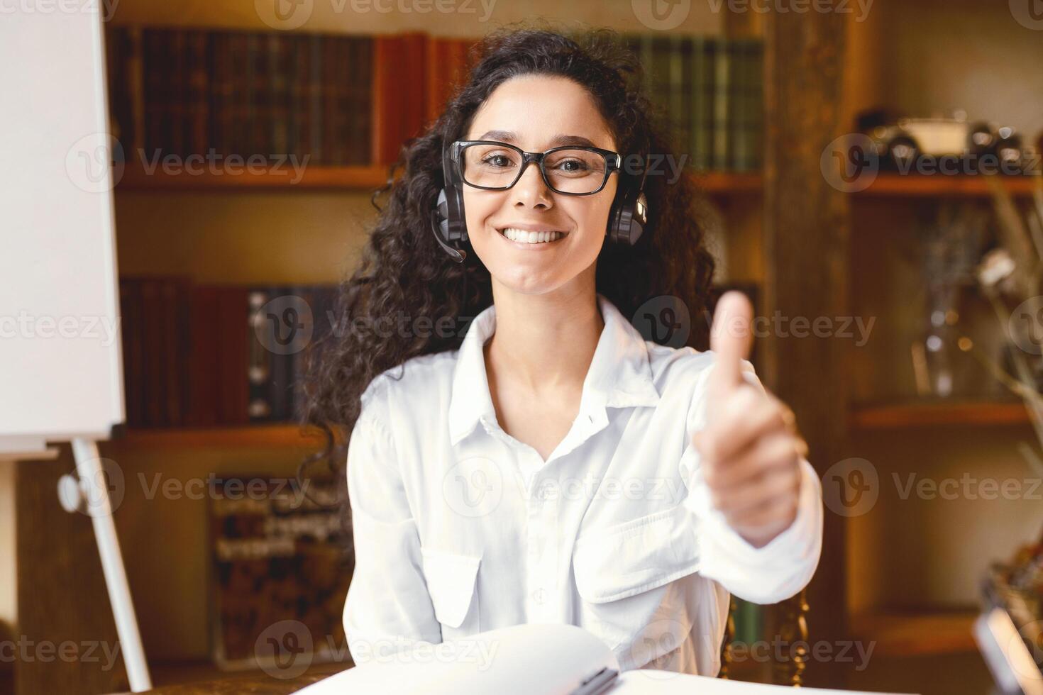 I Like E-Learning. Happy Smiling Female Student In Headset Gesturing Thumbs Up To Camera Approving Educational Online Course Sitting At Home. Distance Learning, Remote Study And Modern Education photo