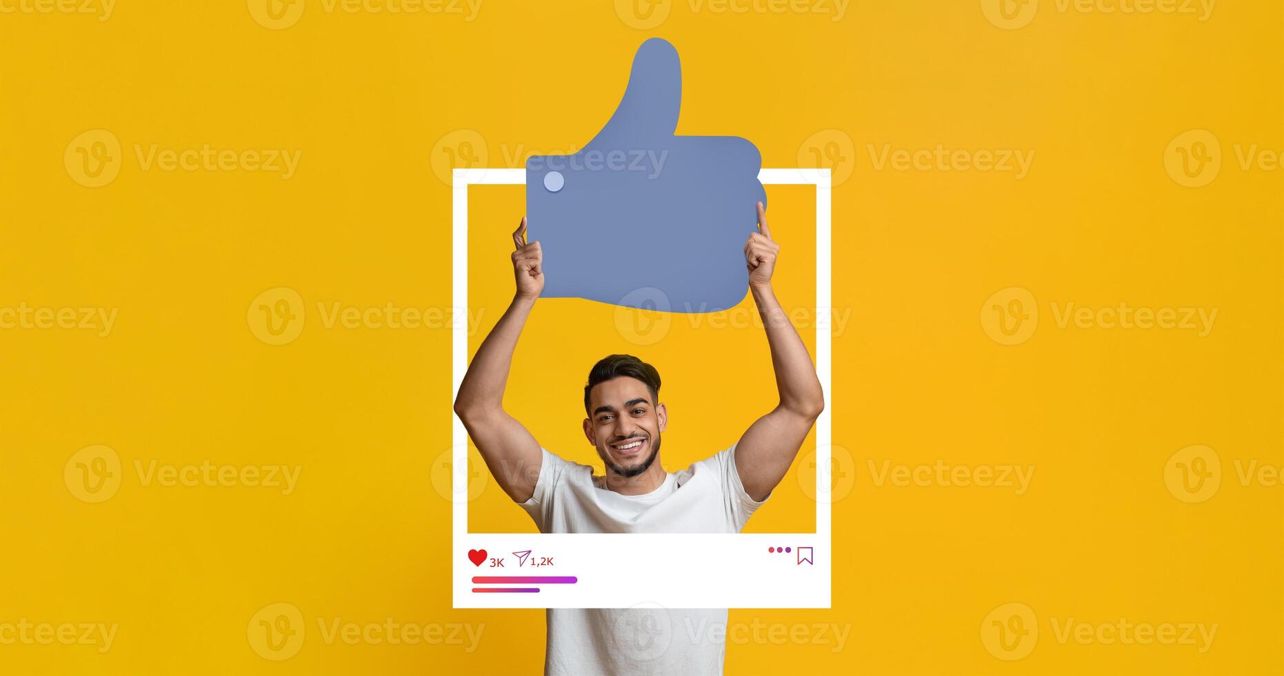 A young man smiles while holding a large thumbs-up symbol in front of a bright yellow backdrop. He interacts with social media content, showcasing a positive vibe that attracts online followers. photo
