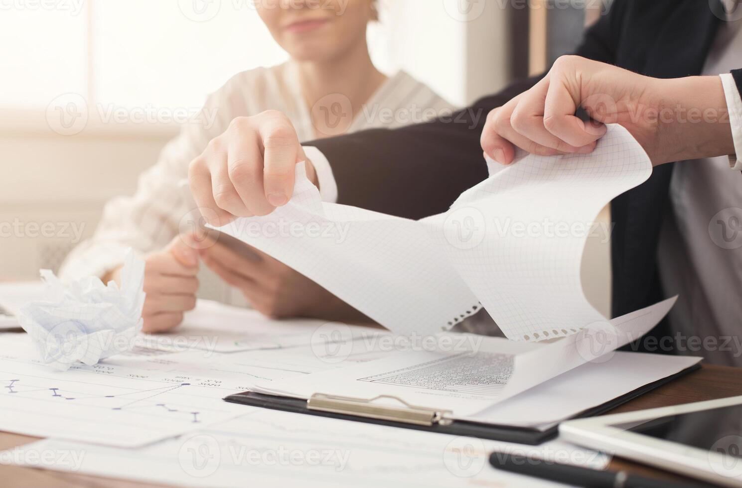 Angry businessman tearing up a document, contract or agreement in office, copy space. Closeup of man hands, selective focus photo