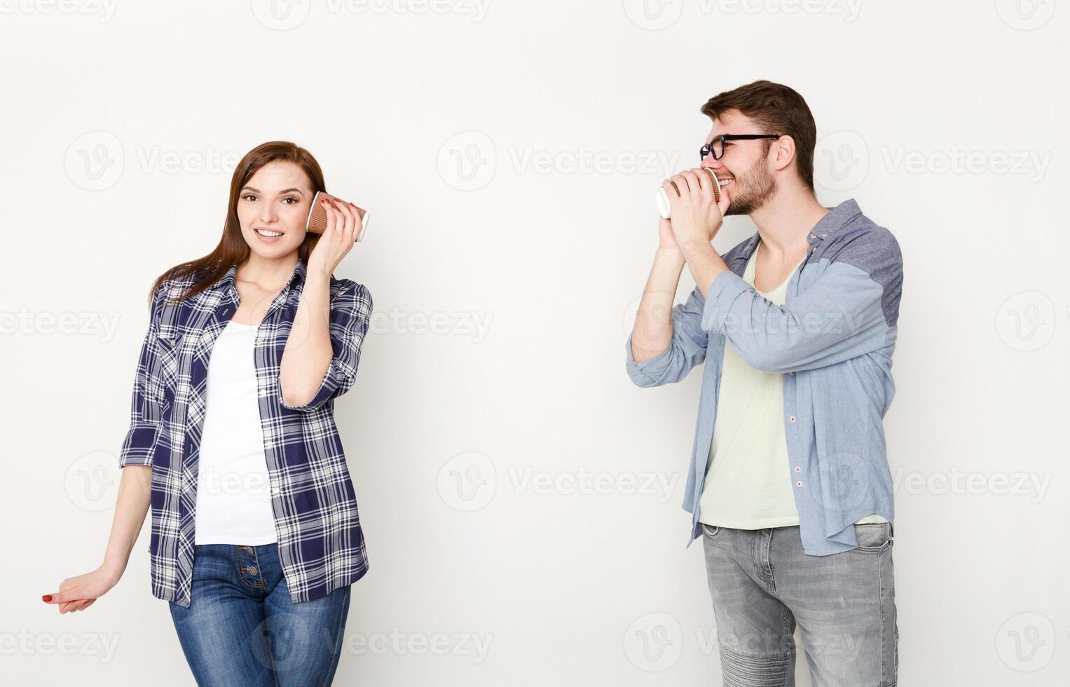 Communication and fun. Young casual couple talking through tin can phone, isolated on white background photo