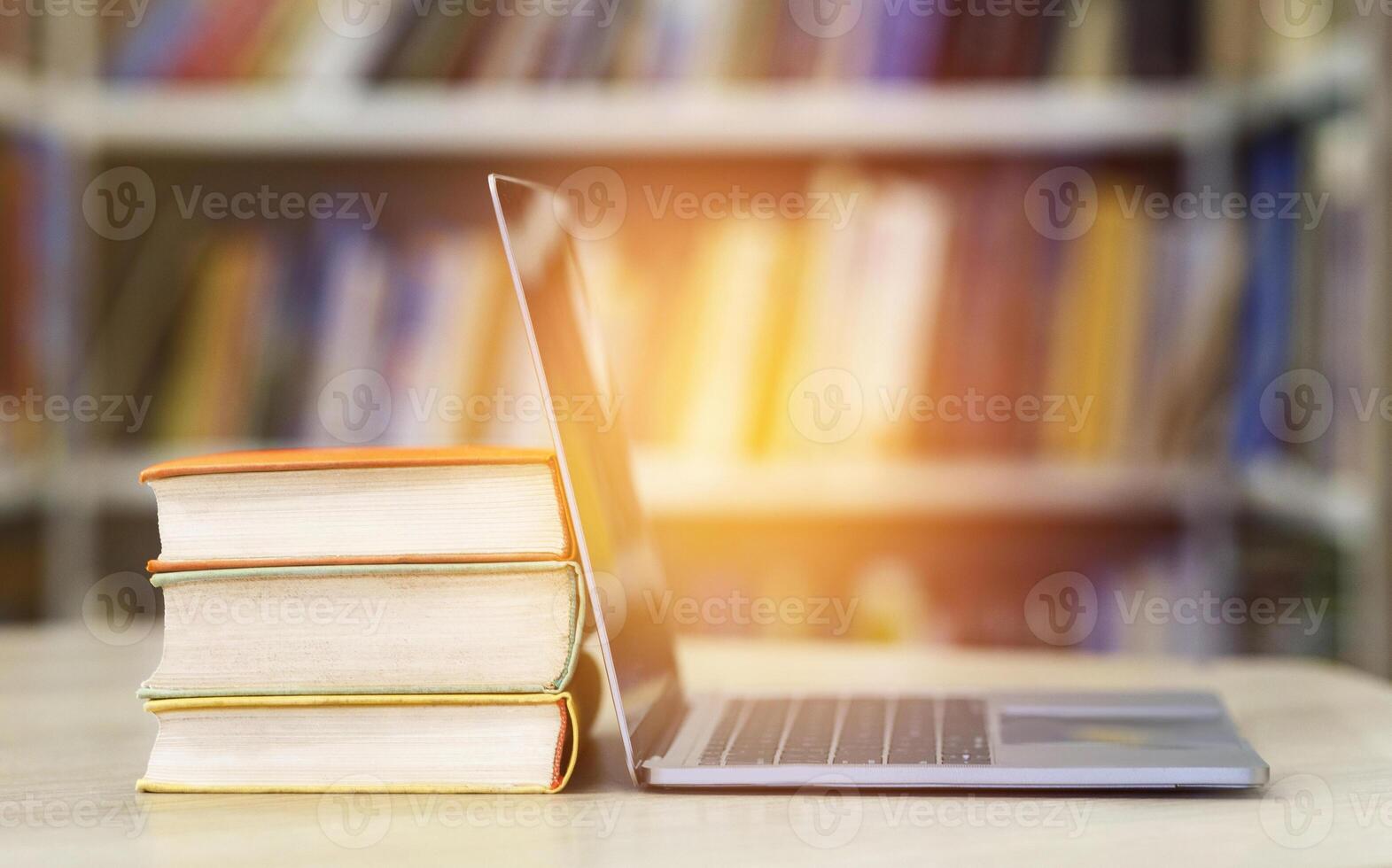 Digital Education And E-learning. Open laptop and stack of old books in blur school library or classroom background photo