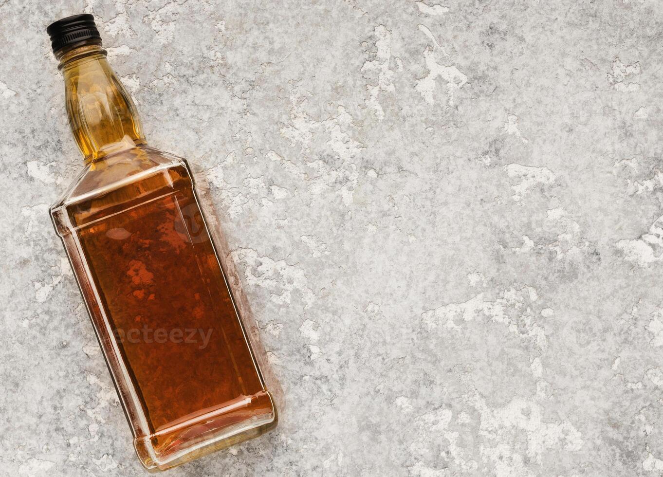 Elite alcohol bottle on gray stone background. Mockup for whiskey, brandy or cognac advertisement, top view, copy space photo