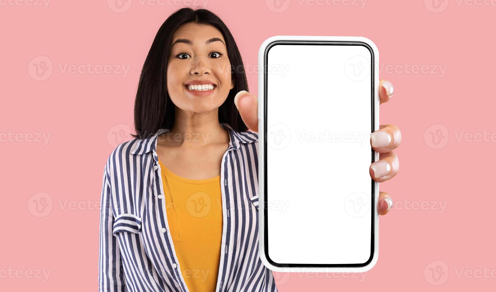 Great Mobile Offer. Excited Asian Lady Showing Big Smartphone With Empty Screen To Camera Advertising New Application For Phone Standing On Pink Studio Background. Mockup photo
