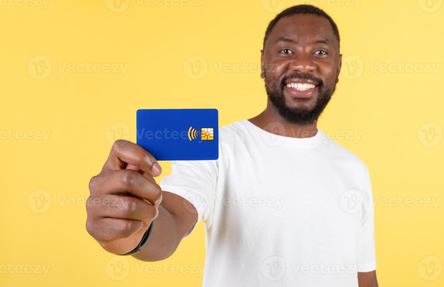 Smiling Black Man Showing His Credit Card To Camera Advertising Great Bank Offer Posing Standing On Yellow Background, Studio Shot. Payment And Financial Safety Concept. Selective Focus photo