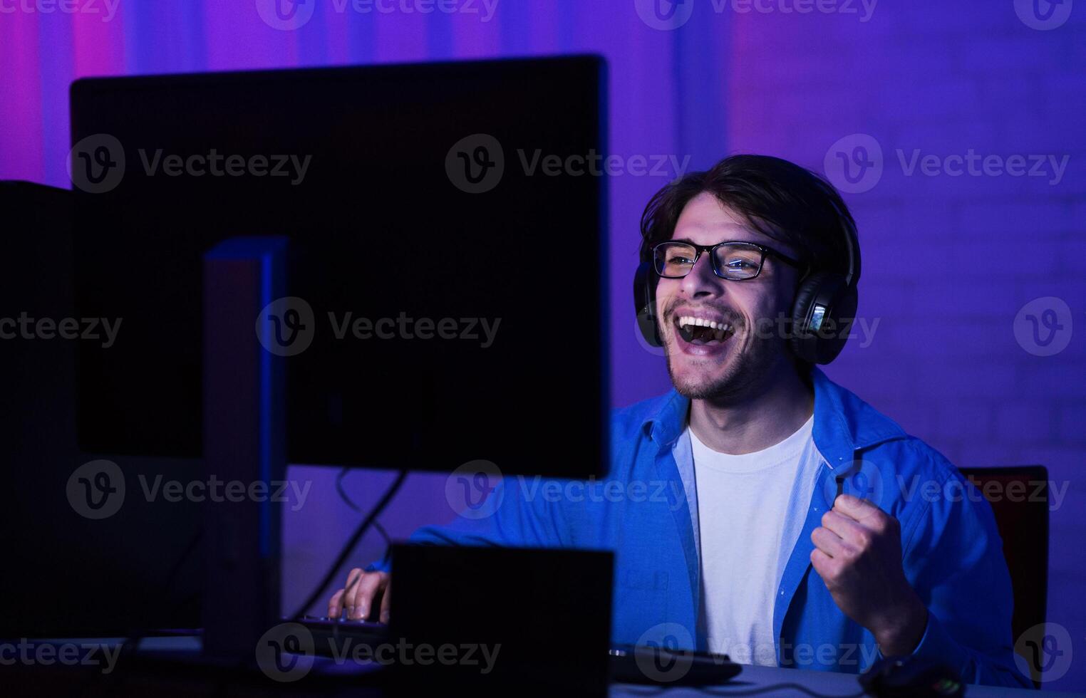 Overjoyed man win online game, wearing headset and glasses, playing all night at home photo