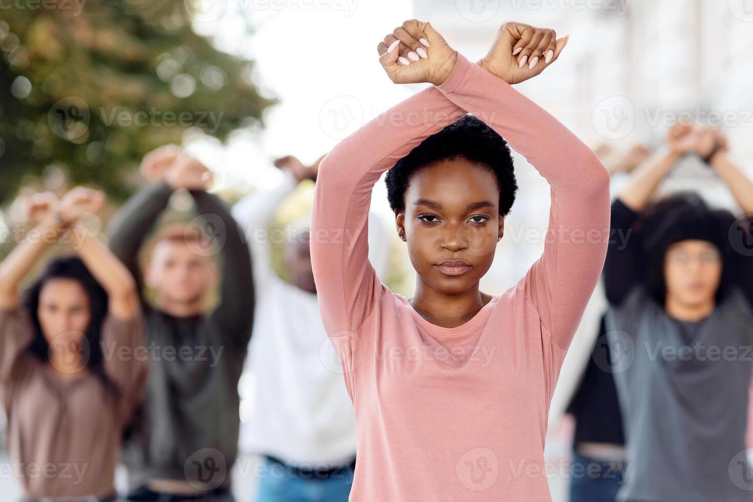 African american woman guiding multiracial group of activists, crossing fists up, showing unity and strength, millennial strikers different nationalities walking by street, making riot photo