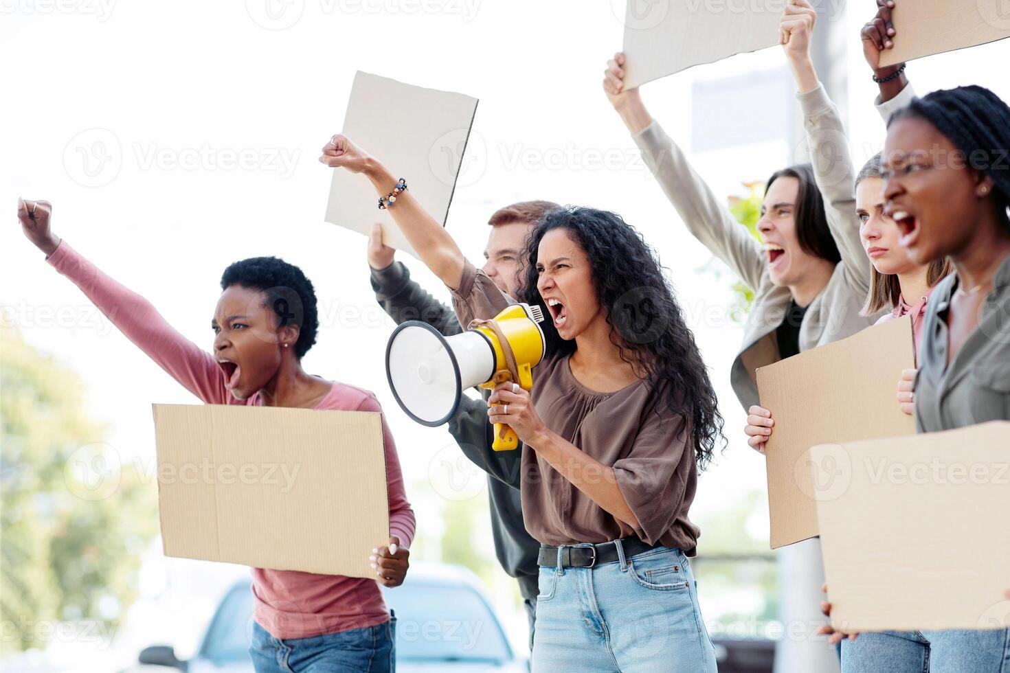International group of people making strike on the street, using loudspeaker, holding blank placards, side view, copy space. Angree demonstrators fighting against war or animal abuse photo