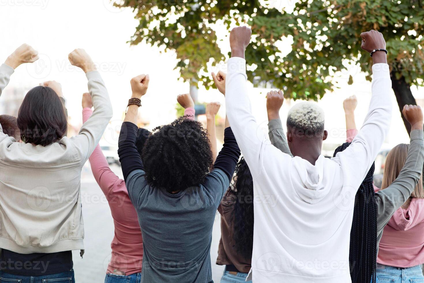 Back vire of international group of people making strike on the street, chanting slogans and raising fists up, demanding from government saving planet, reducing pollution. Riot, demonstration, strike photo