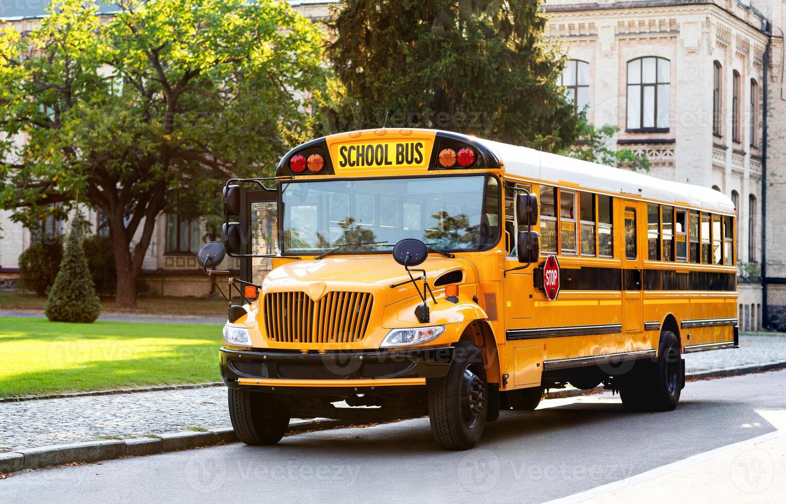 Classic yellow school bus with its red stop sign standing on the road, retro vehicle awaiting students on the parking area, ready to pick up pupils, transportation concept, copy space photo
