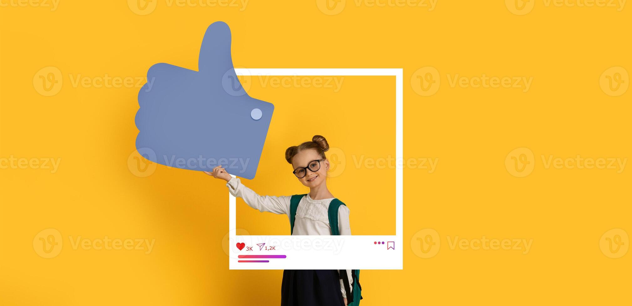 A young girl, wearing glasses and twin buns, enthusiastically holds a large thumbs up sign. The vibrant yellow background and social media frame create a lively atmosphere perfect for online content. photo