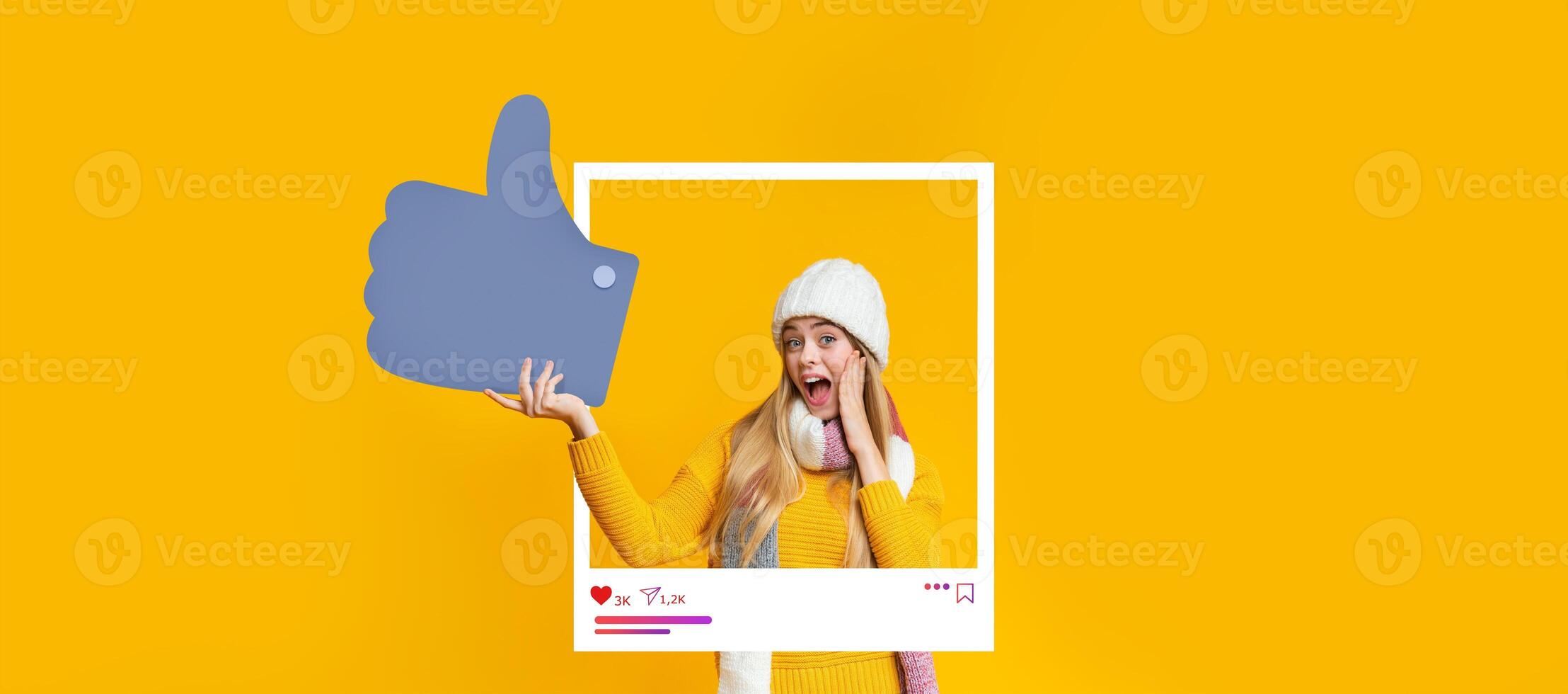 A young woman expressing excitement with a thumbs-up gesture. She wears a cozy yellow sweater and a warm hat, surrounded by a bright yellow background that enhances her joyful expression. photo