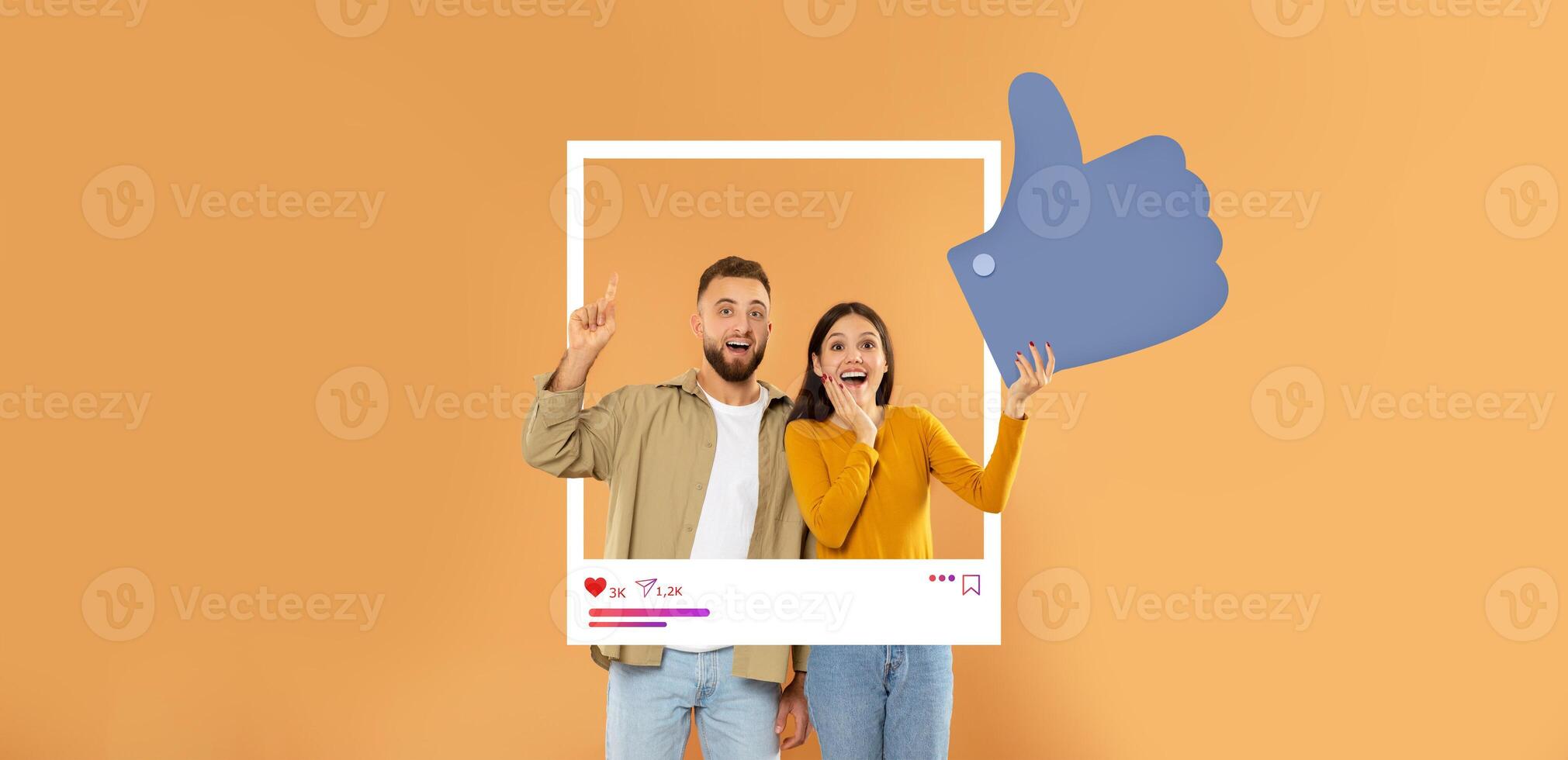 A happy couple poses in front of a warm orange background, celebrating social media interaction. They enthusiastically display thumbs up, embodying positive influencer culture. photo