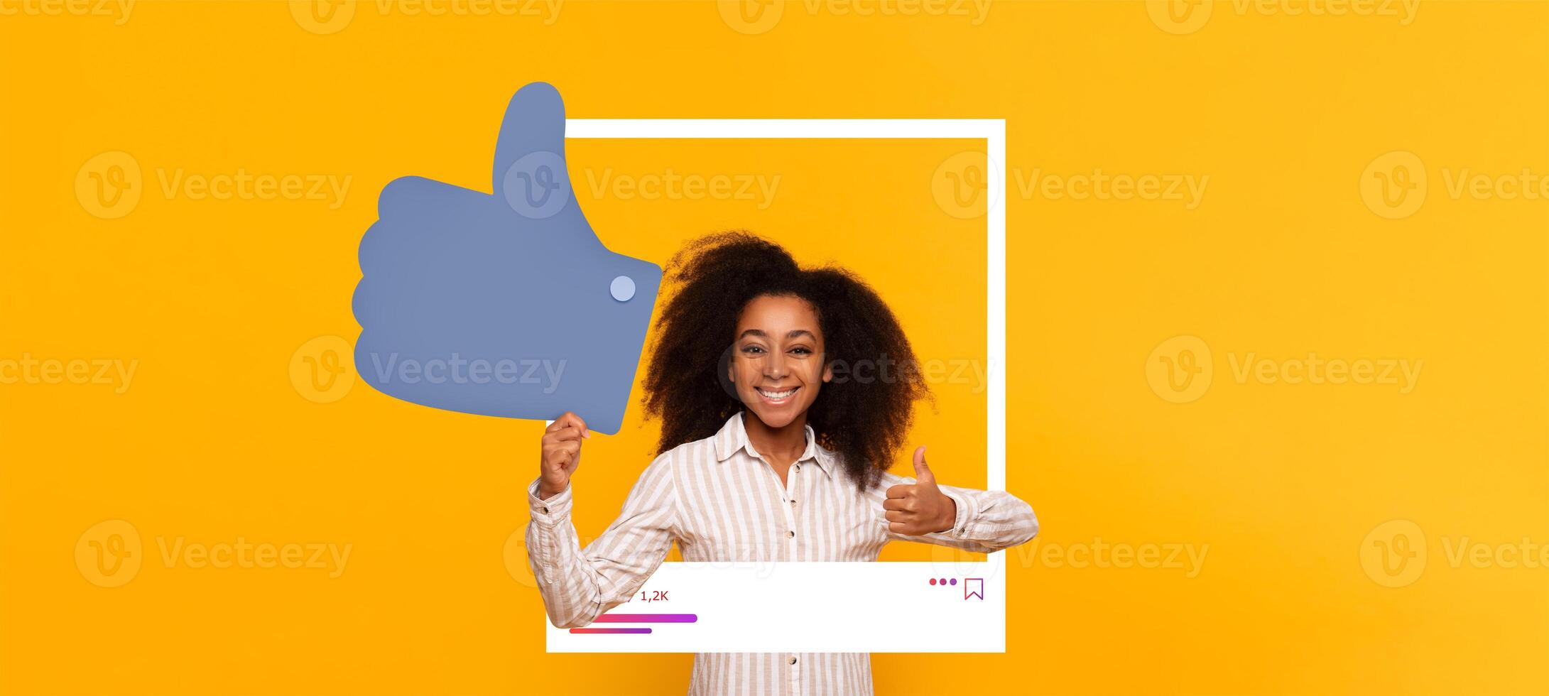 A young girl smiles while holding a large thumbs up symbol in front of a vivid yellow background. She is promoting positive interaction on social media and celebrating her influence. photo