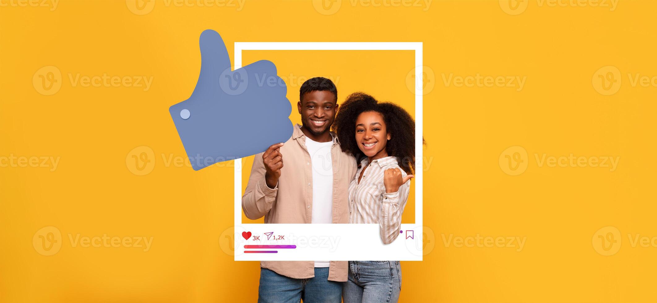 A young couple stands smiling in front of a bright yellow background, showcasing a playful thumbs-up gesture. They appear to celebrate their social media success as influencers. photo