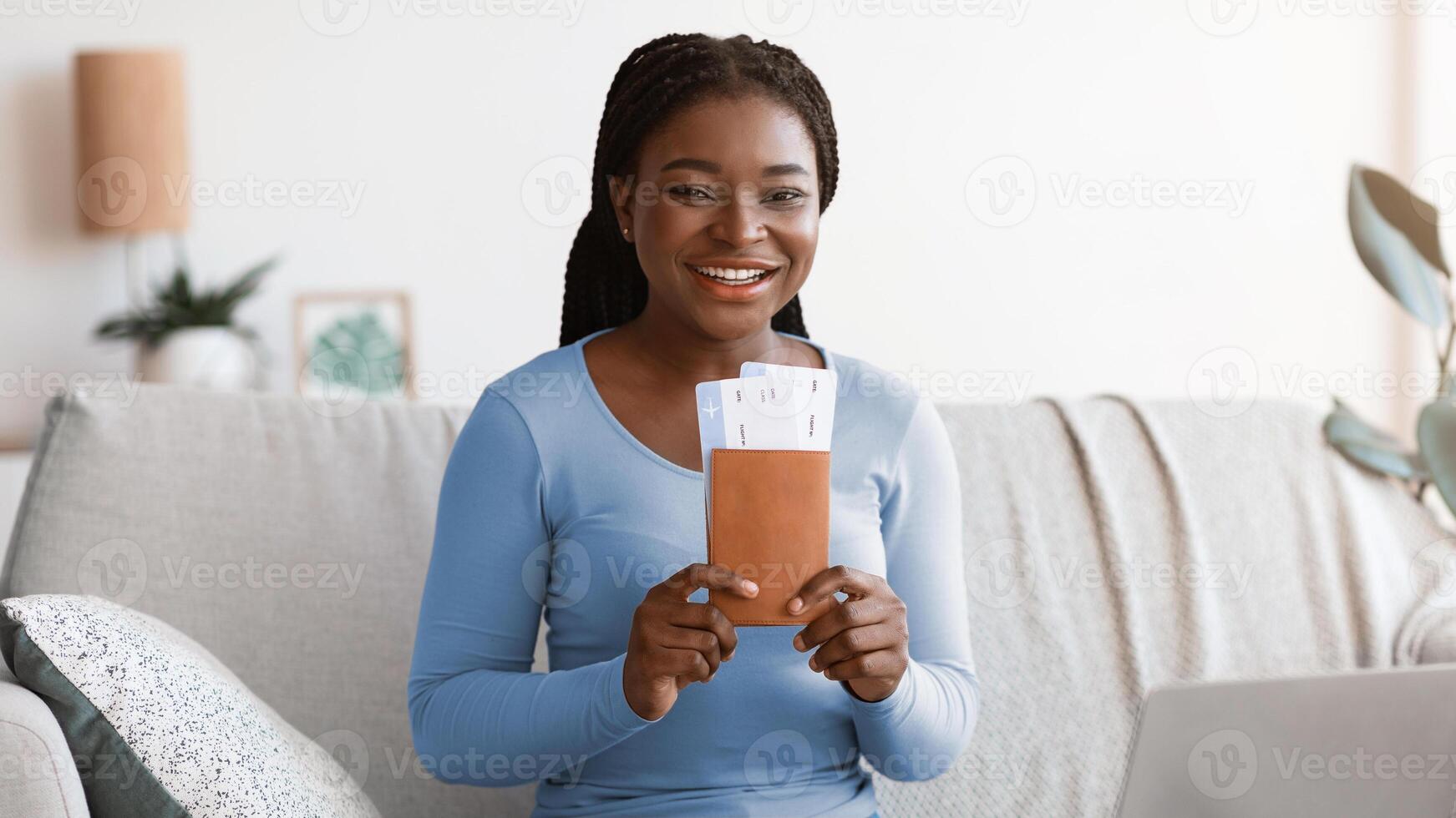 Ready For Vacation. Happy Black Woman Holding Passports And Tickets At Home, Positive African Lady Sitting At Table With Map And Laptop Preparing For Future Travel, Smiling At Camera, Copy Space photo