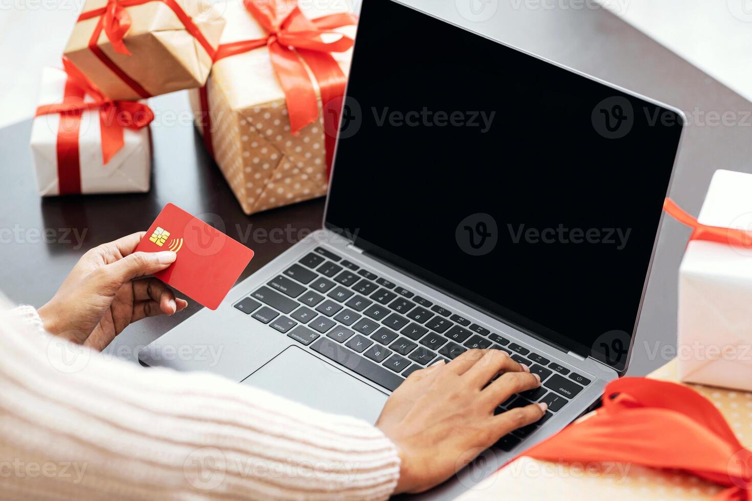 Online Holiday Shopping. Over the shoulder view of african american woman holding red credit card and using computer with black blank screen for mockup template, female buyer ordering presents photo