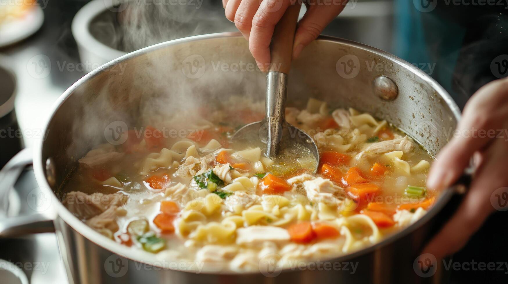 Hands stirring hot chicken noodle soup in a large pot. photo