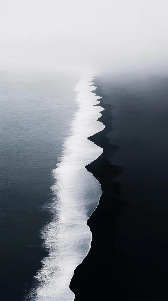 Monochromatic Coastal Beauty A Striking Black Sand Beach Meets the Ocean in a Misty Landscape photo