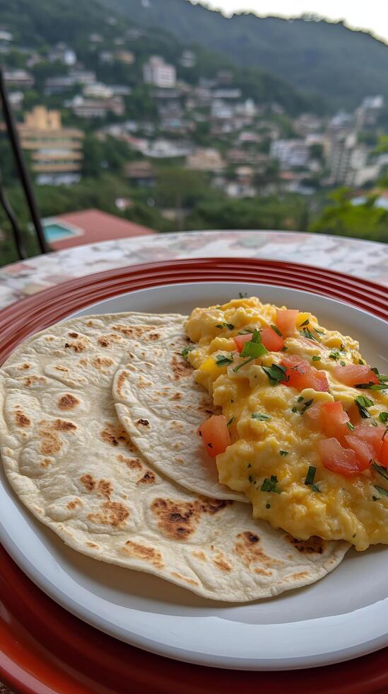 Scrumptious Scrambled Eggs with Cheese and Tomatoes, Served with Warm Tortillas. A delightful breakfast with a breathtaking mountain view, perfect for a relaxing morning. photo