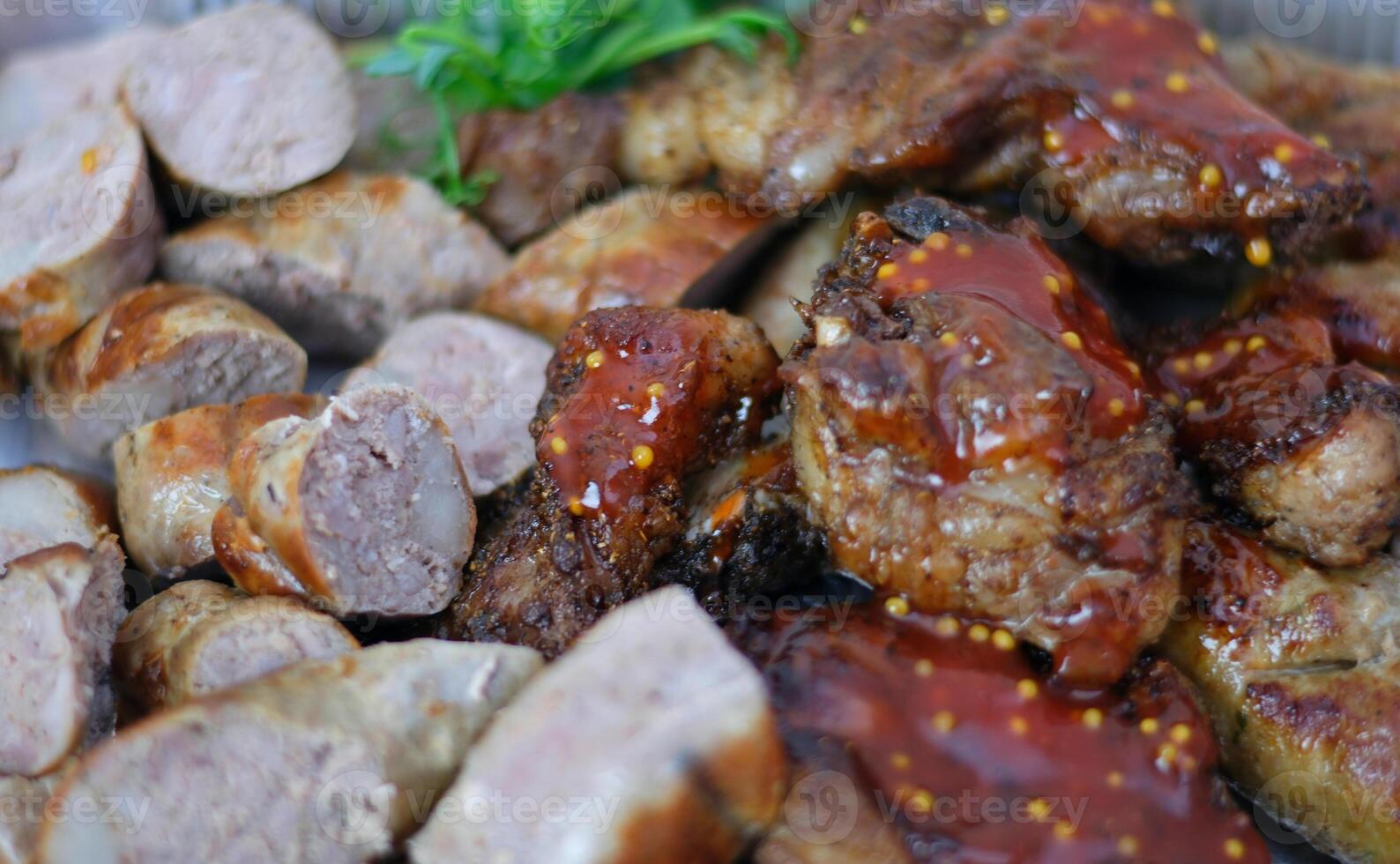 Grilled assorted meat platter with potato wedges and sauces photo
