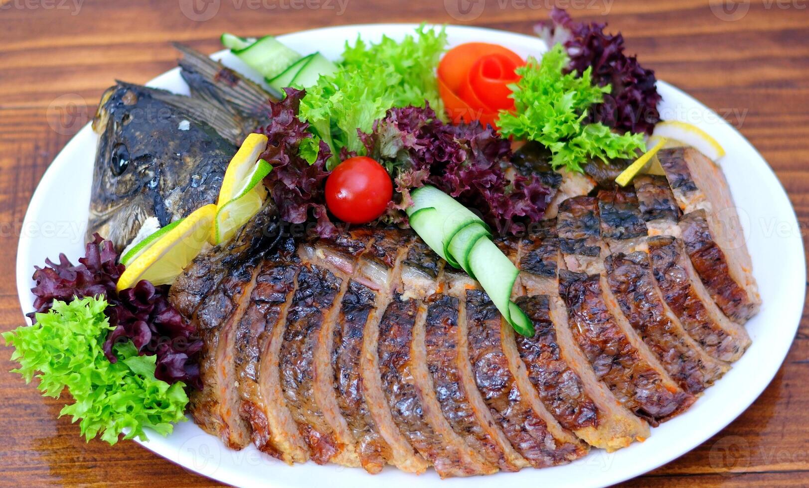 stuffed fish Delicious stuffed carp with lemon and lettuce leaves. photo
