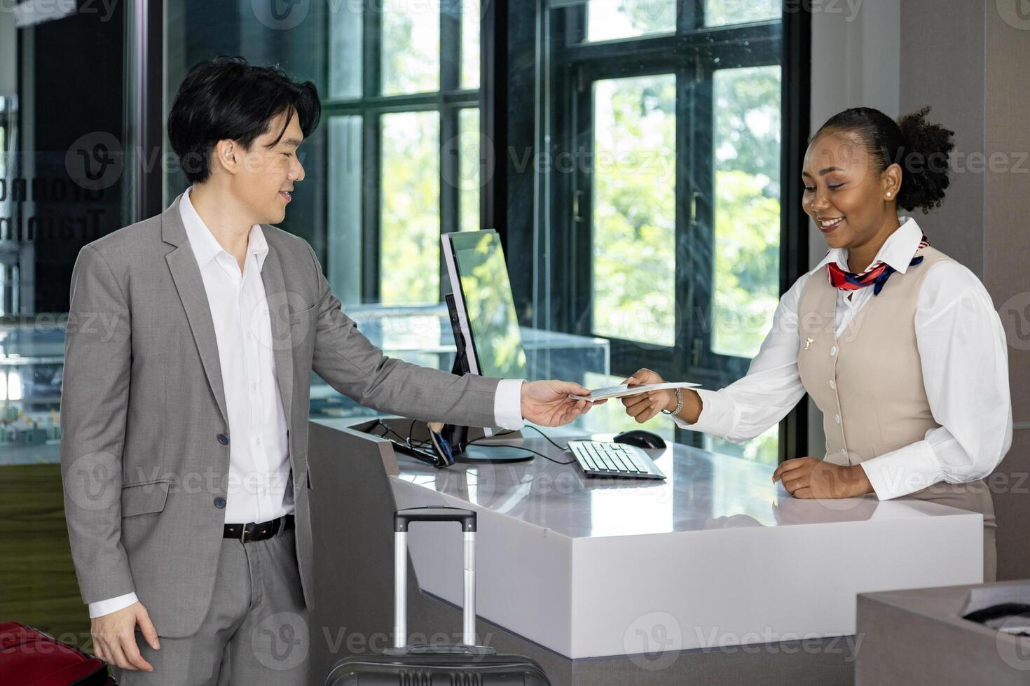 Asian businessman passenger is receiving boarding pass from the airline ground crew at check in counter at departure terminal into the airplane for final inspection before boarding into the plane photo
