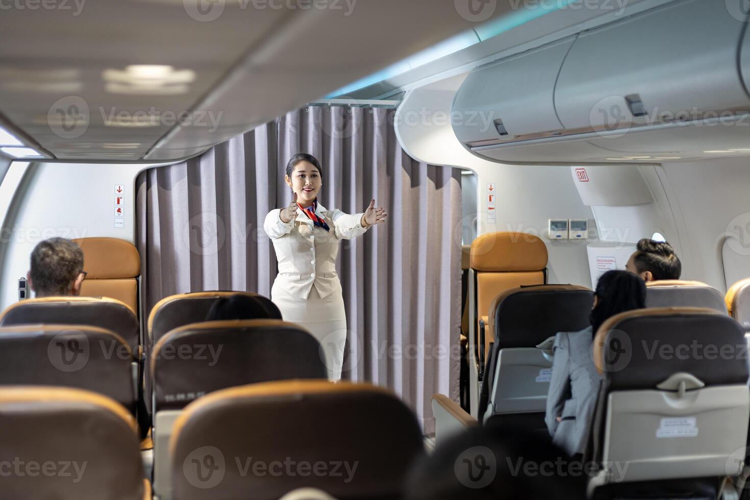 Flight attendant is demonstrating safety procedure showing emergency exit before taking off in the airplane for cabin crew and airline business photo