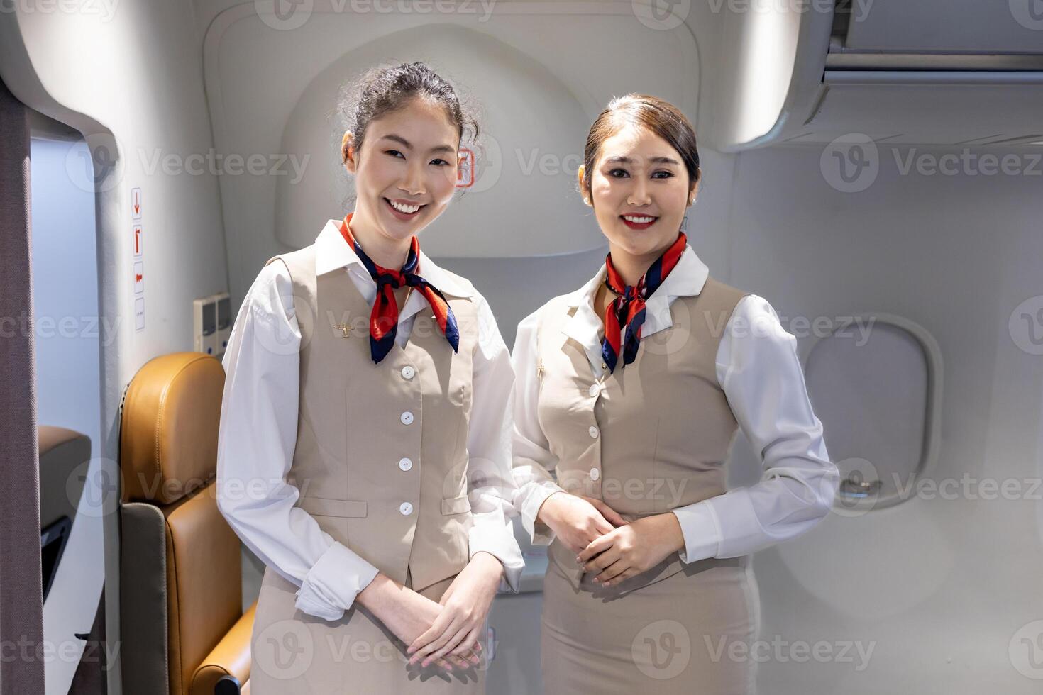 Team of Asian flight attendant posing with smile at middle of the aisle inside aircraft for welcoming passenger on board with seat on background photo